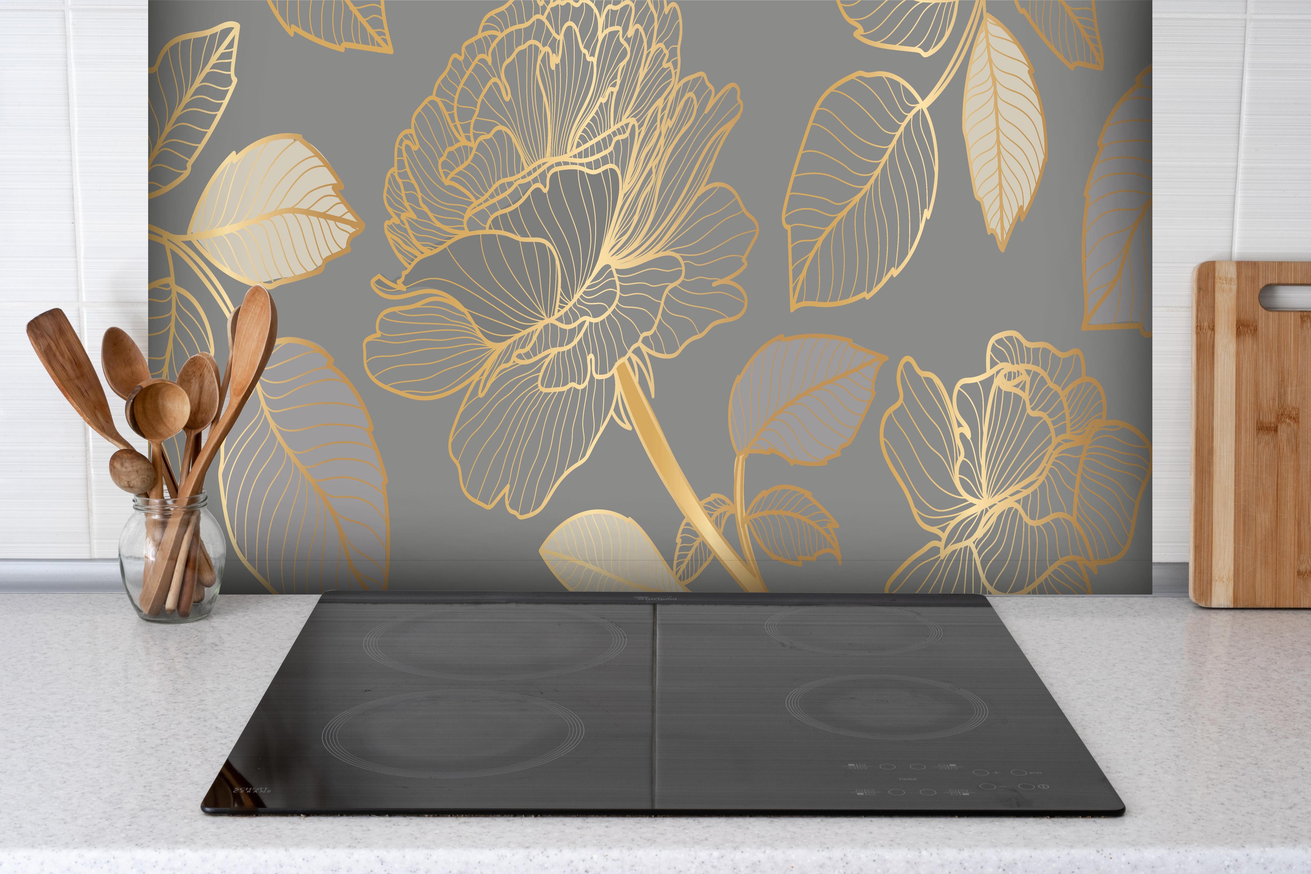 Spritzschutz - Elegantes Blumenmuster in Gold und Grau hinter einem Cerankochfeld zwischen Holz-Kochutensilien