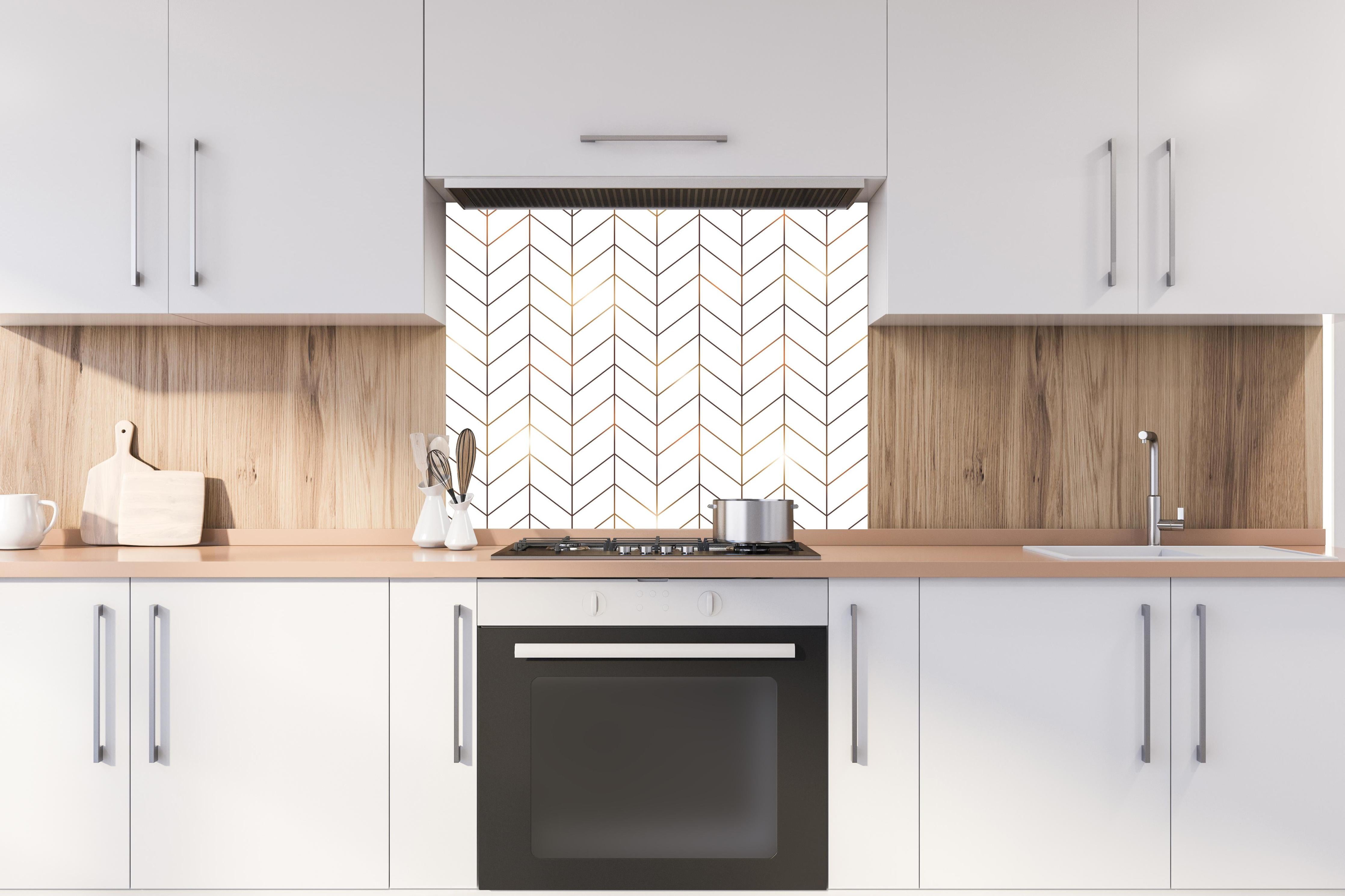 Spritzschutz - Elegantes Chevron Muster in Gold-Schwarz hinter einem Cerankochfeld zwischen Holz-Kochutensilien