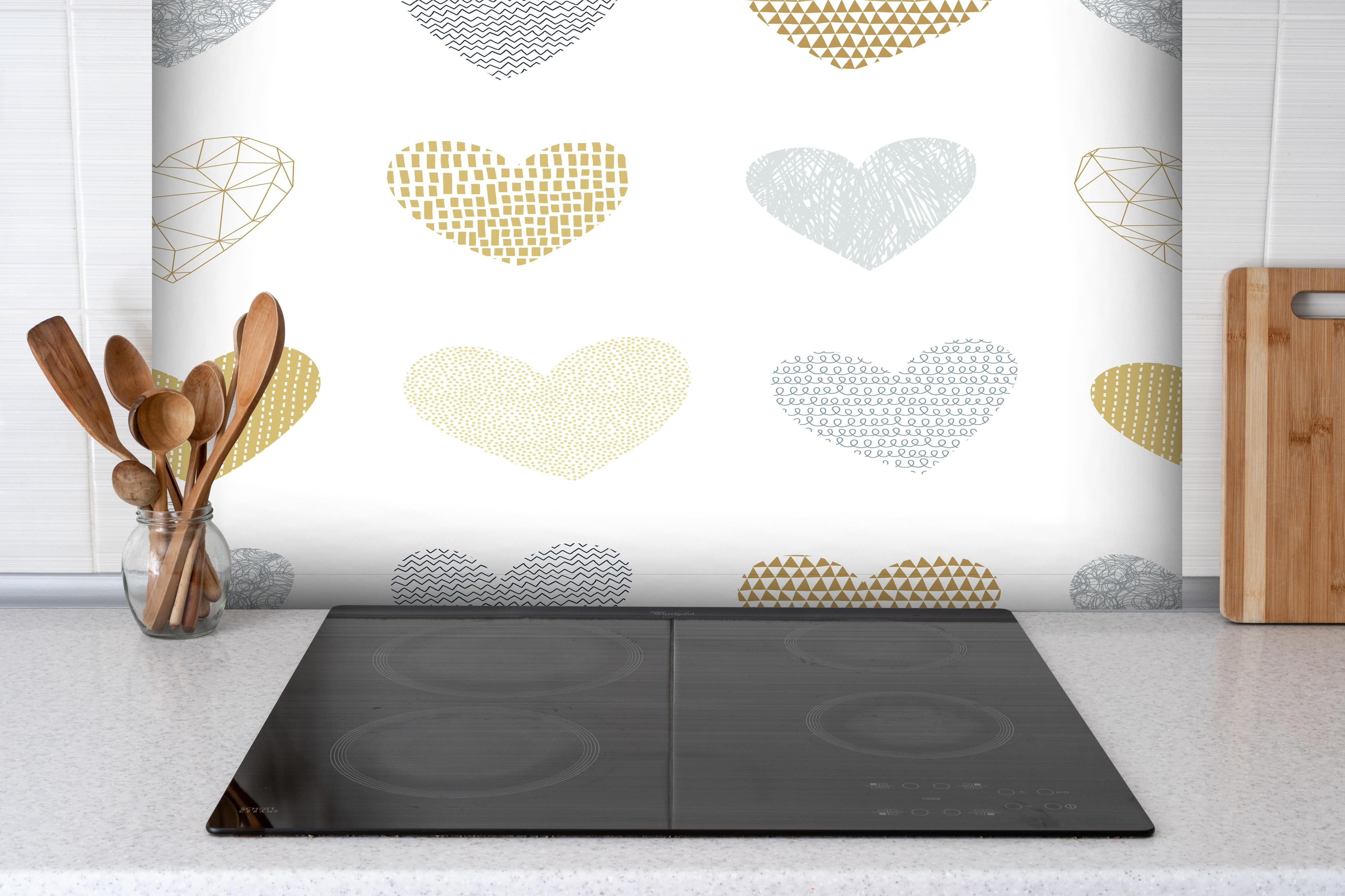 Spritzschutz - Elegantes Herz-Muster in Gold und Grau hinter einem Cerankochfeld zwischen Holz-Kochutensilien