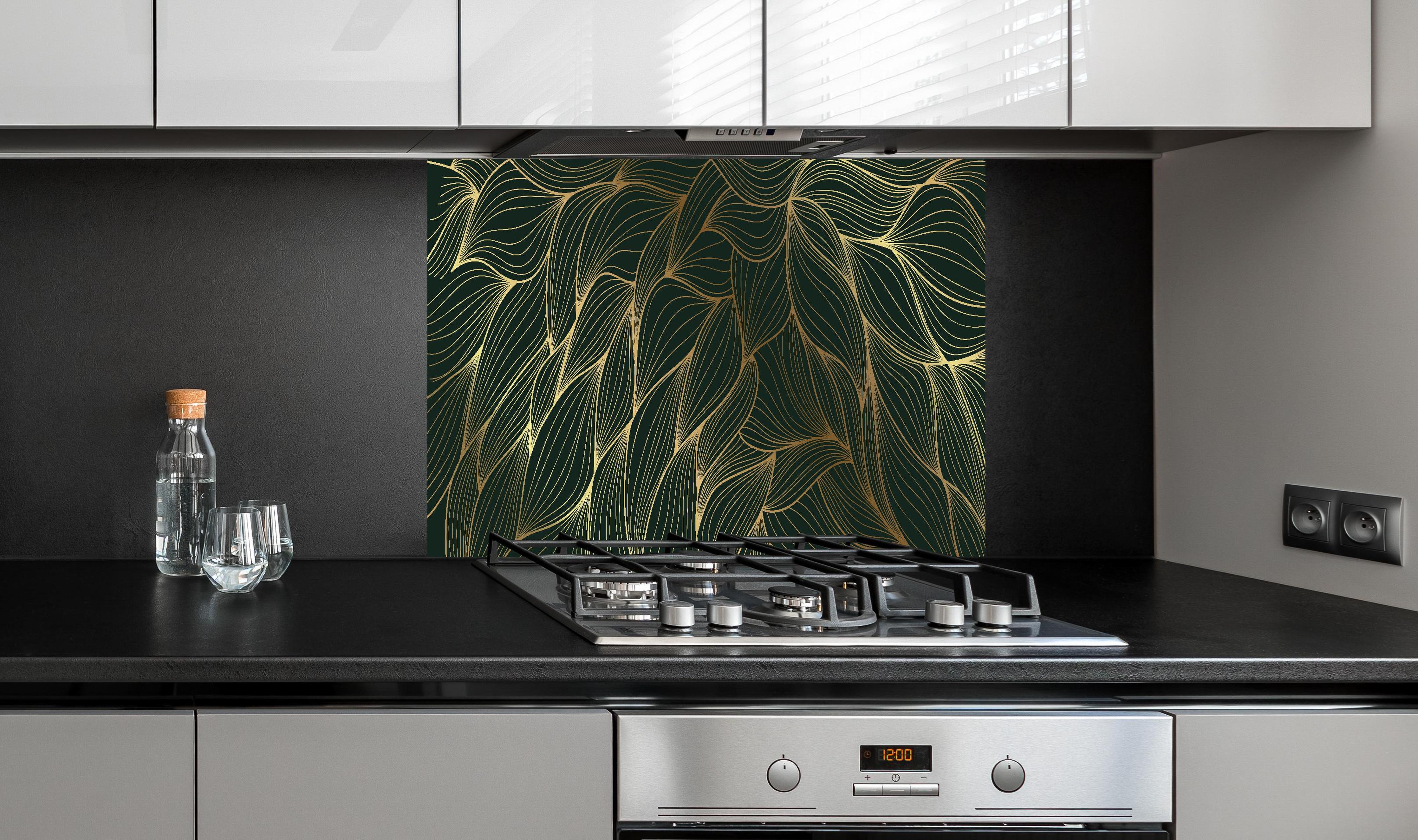 Spritzschutz - Elegantes Wellenmuster in Gold und Dunkelgrün hinter einem Cerankochfeld zwischen Holz-Kochutensilien