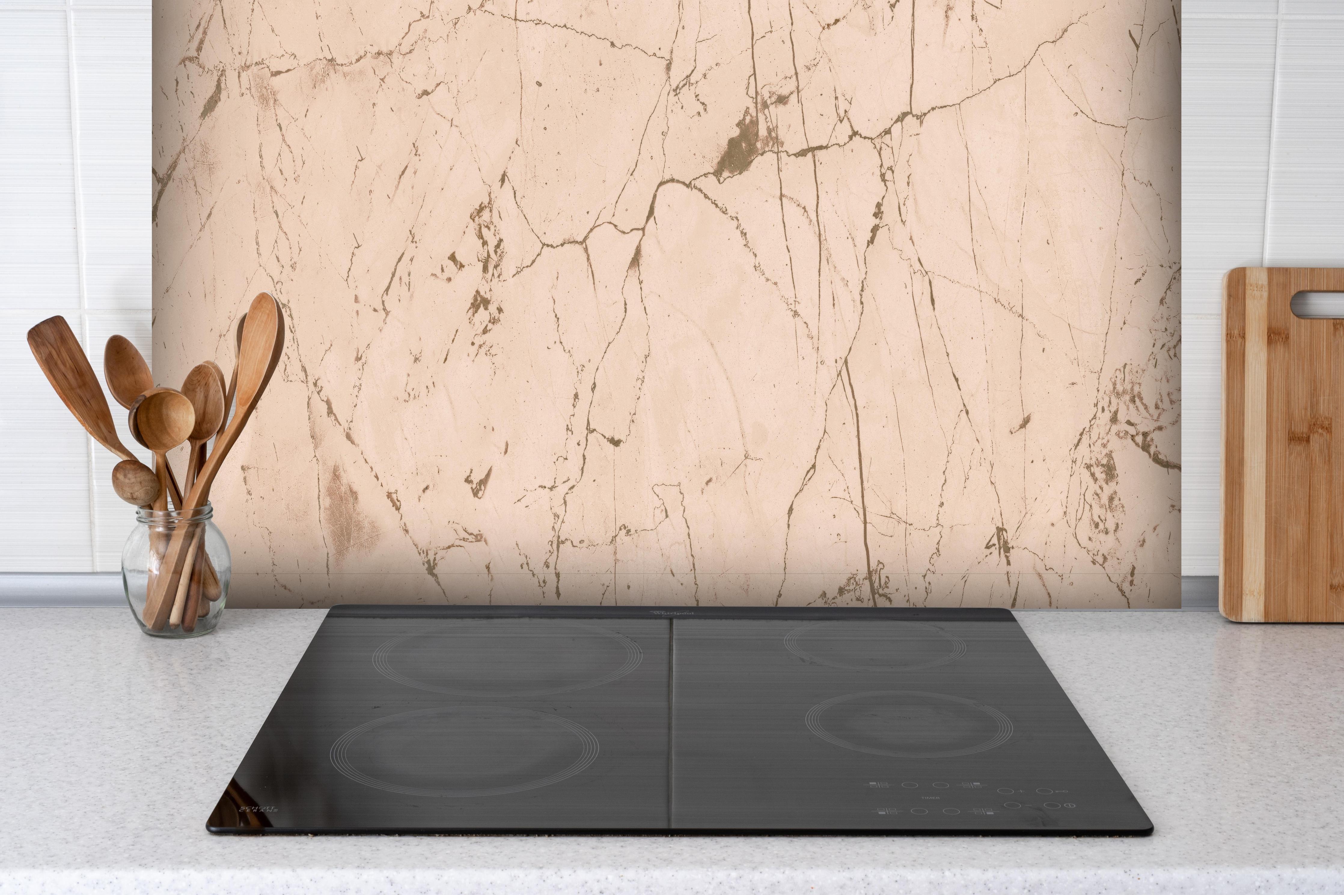 Spritzschutz - Elfenbeinfarbener OnyxmarmoR hinter einem Cerankochfeld zwischen Holz-Kochutensilien
