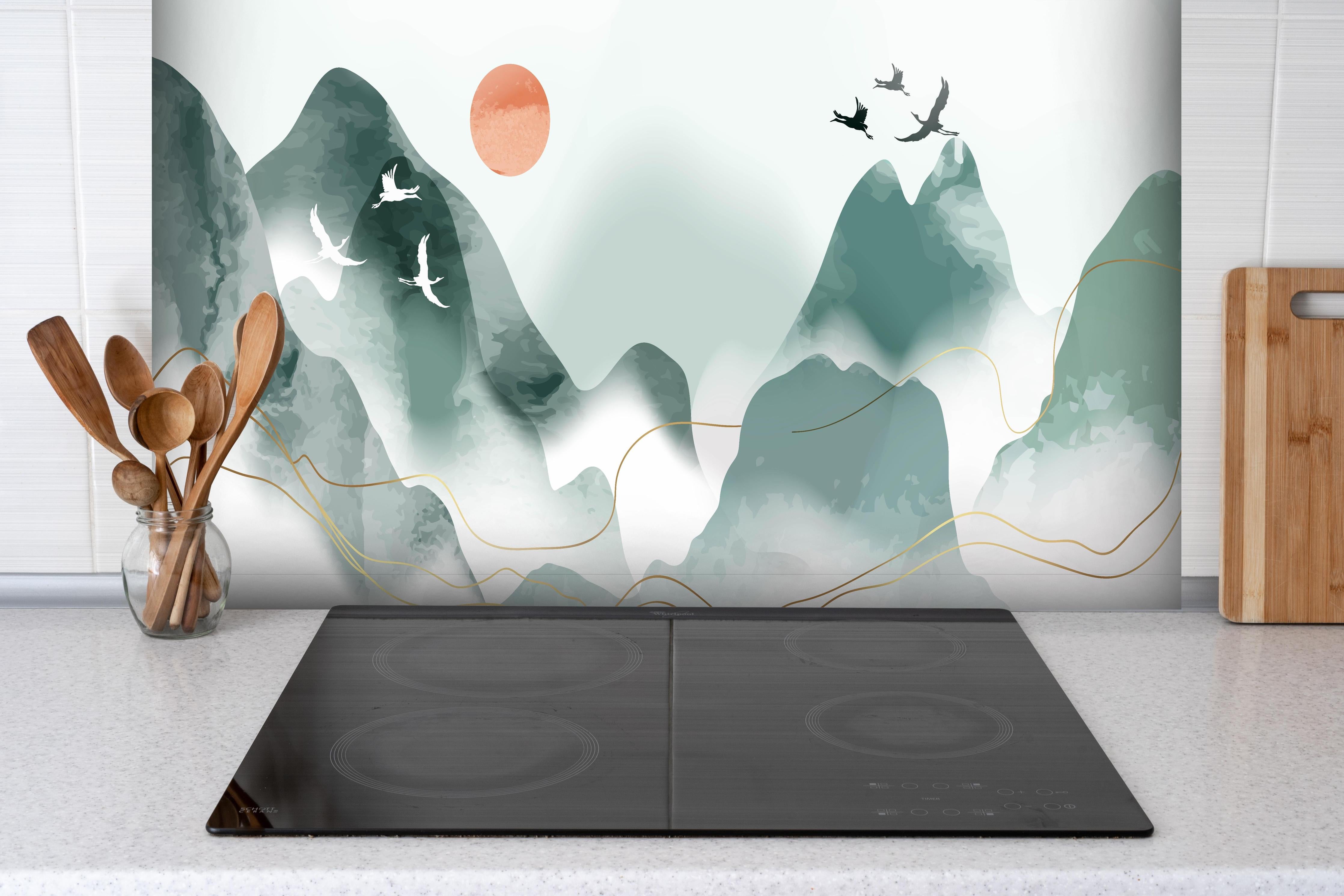 Spritzschutz - Entspannende Berglandschaft bei Sonnenuntergang hinter einem Cerankochfeld zwischen Holz-Kochutensilien