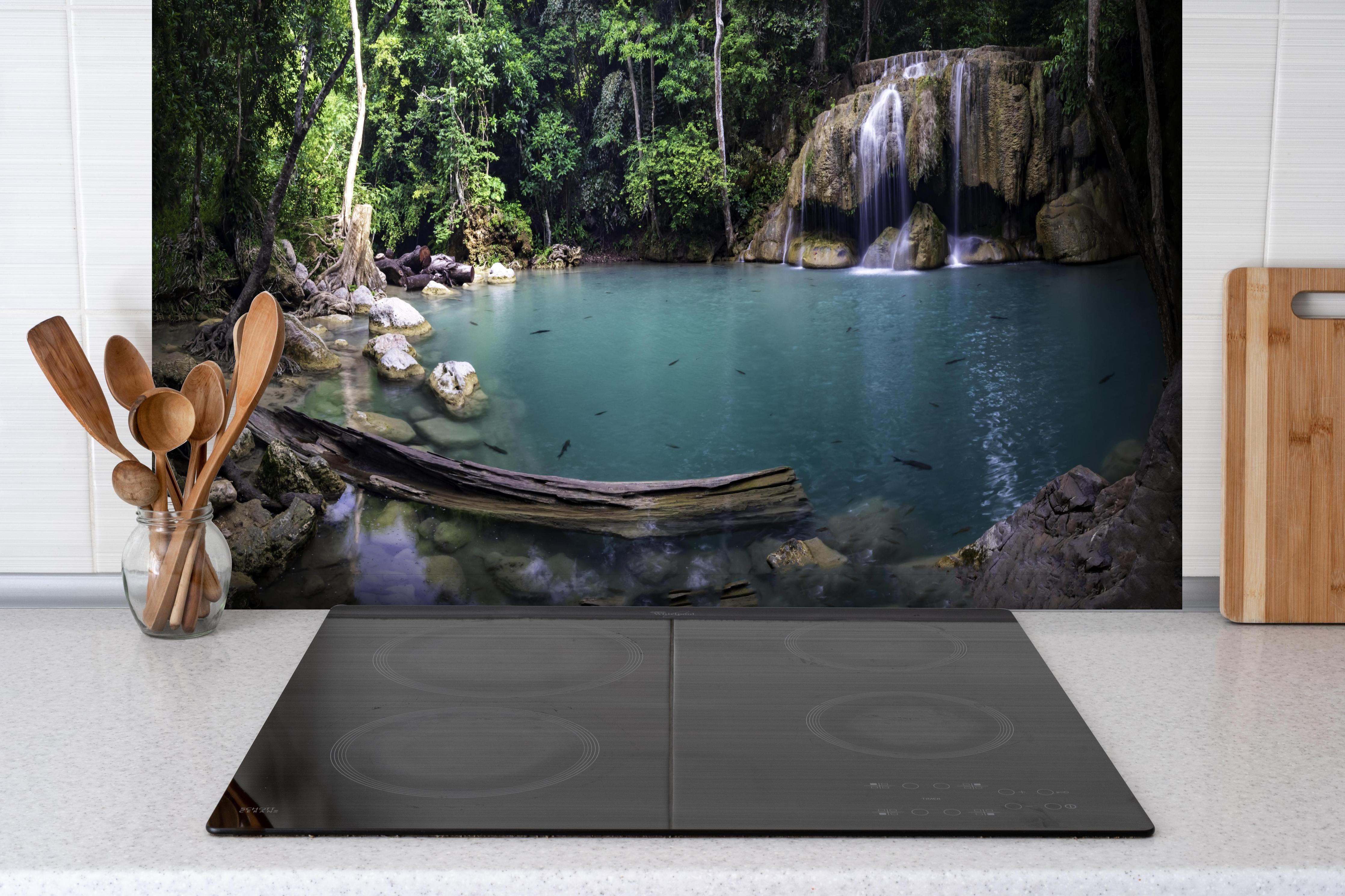 Spritzschutz - Erawan-Wasserfall im tropischen Dschungel Surrou hinter einem Cerankochfeld zwischen Holz-Kochutensilien