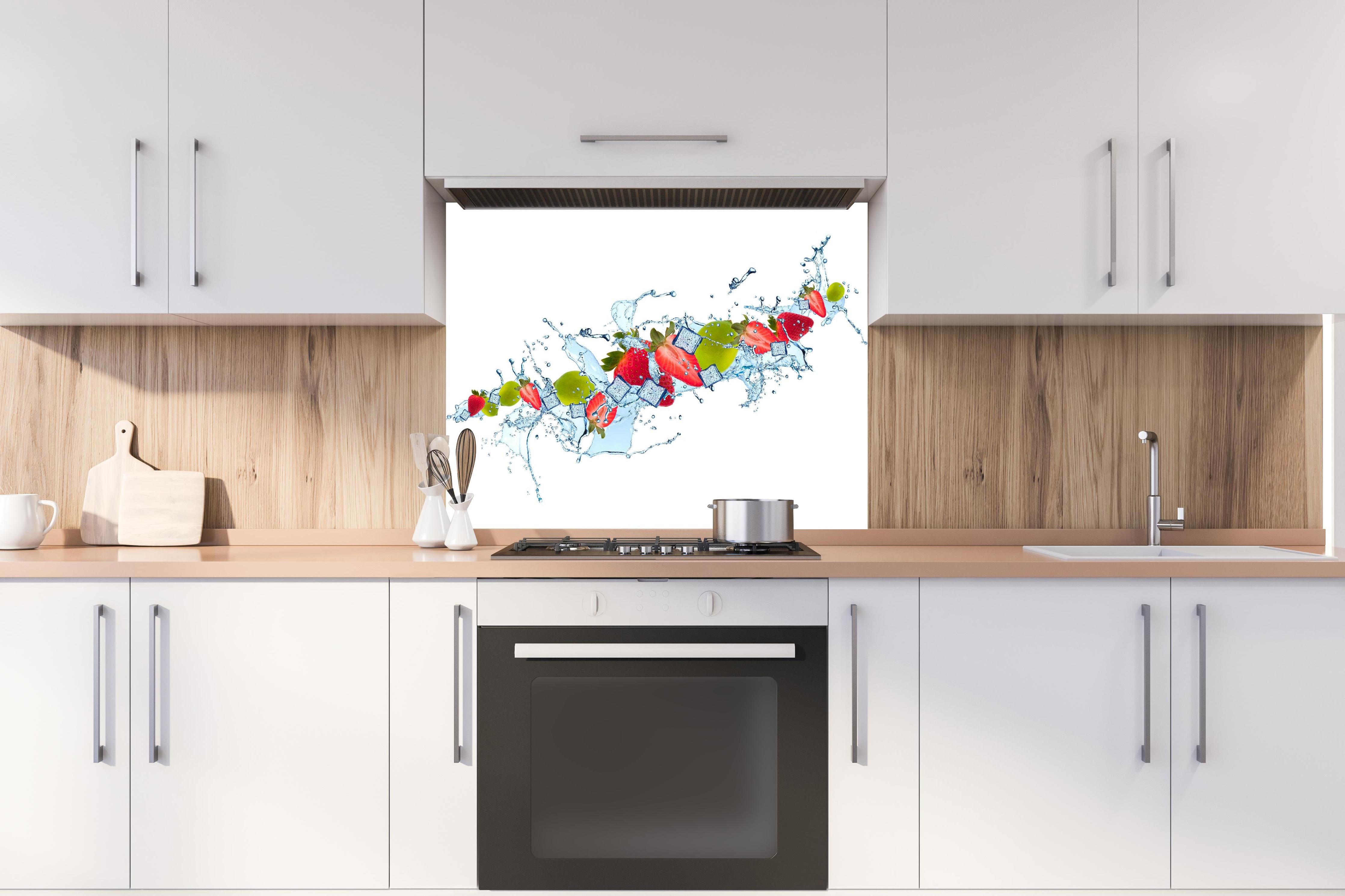 Spritzschutz - Erfrischende Wasserspritzer mit Erdbeere und Limette hinter einem Cerankochfeld zwischen Holz-Kochutensilien