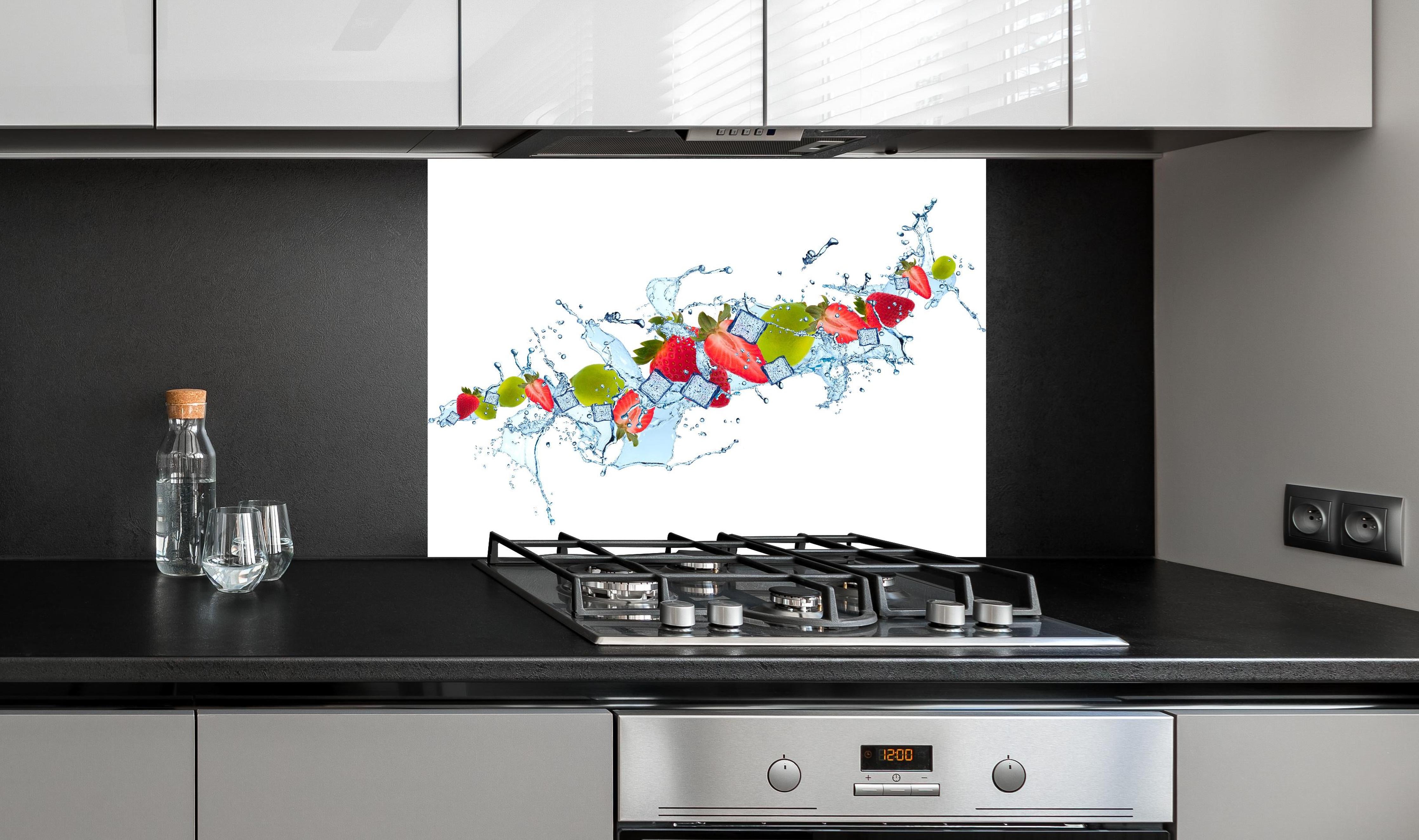 Spritzschutz - Erfrischende Wasserspritzer mit Erdbeere und Limette hinter einem Cerankochfeld zwischen Holz-Kochutensilien