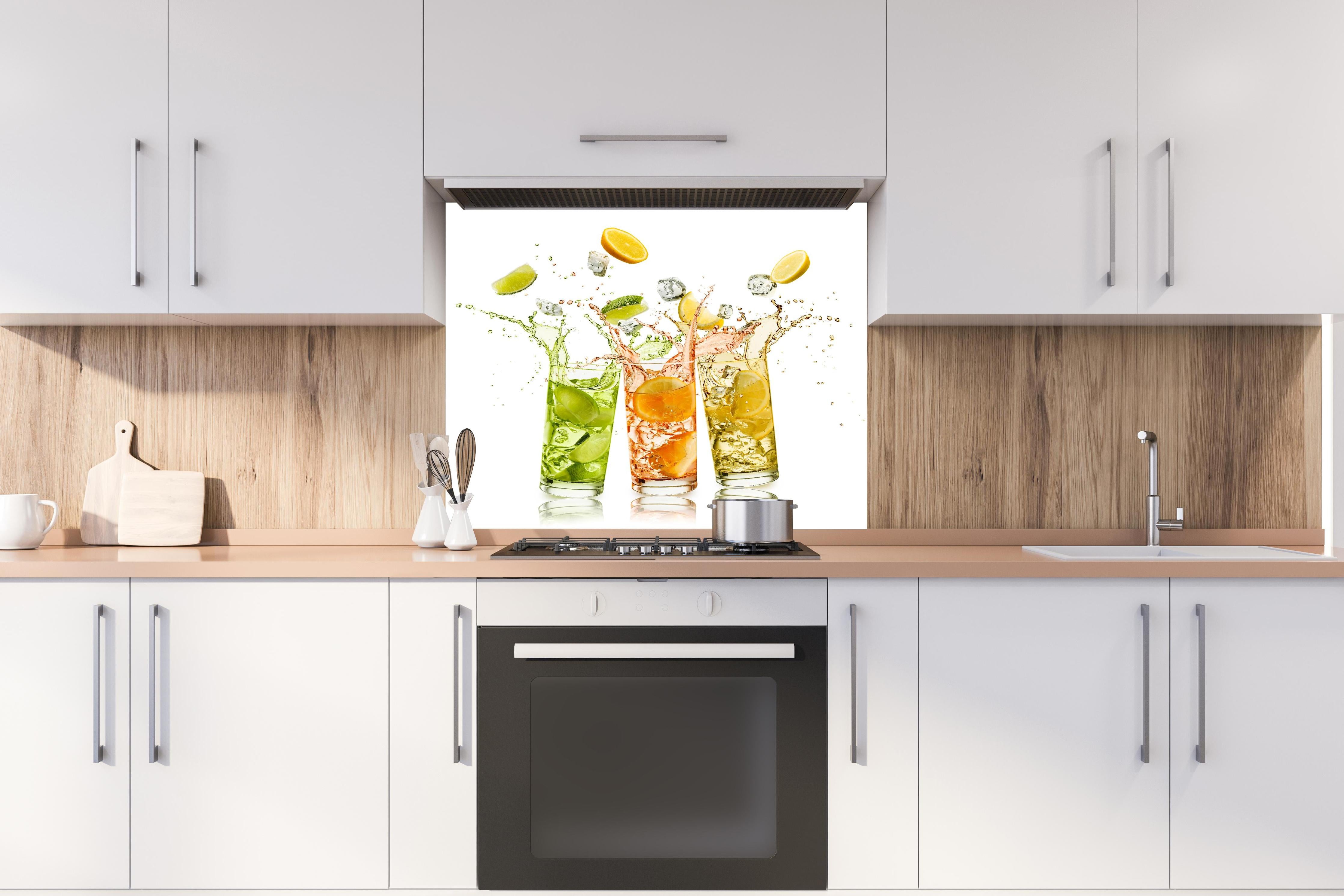 Spritzschutz - Erfrischungsgetränke mit Zitrusfrüchten hinter einem Cerankochfeld zwischen Holz-Kochutensilien