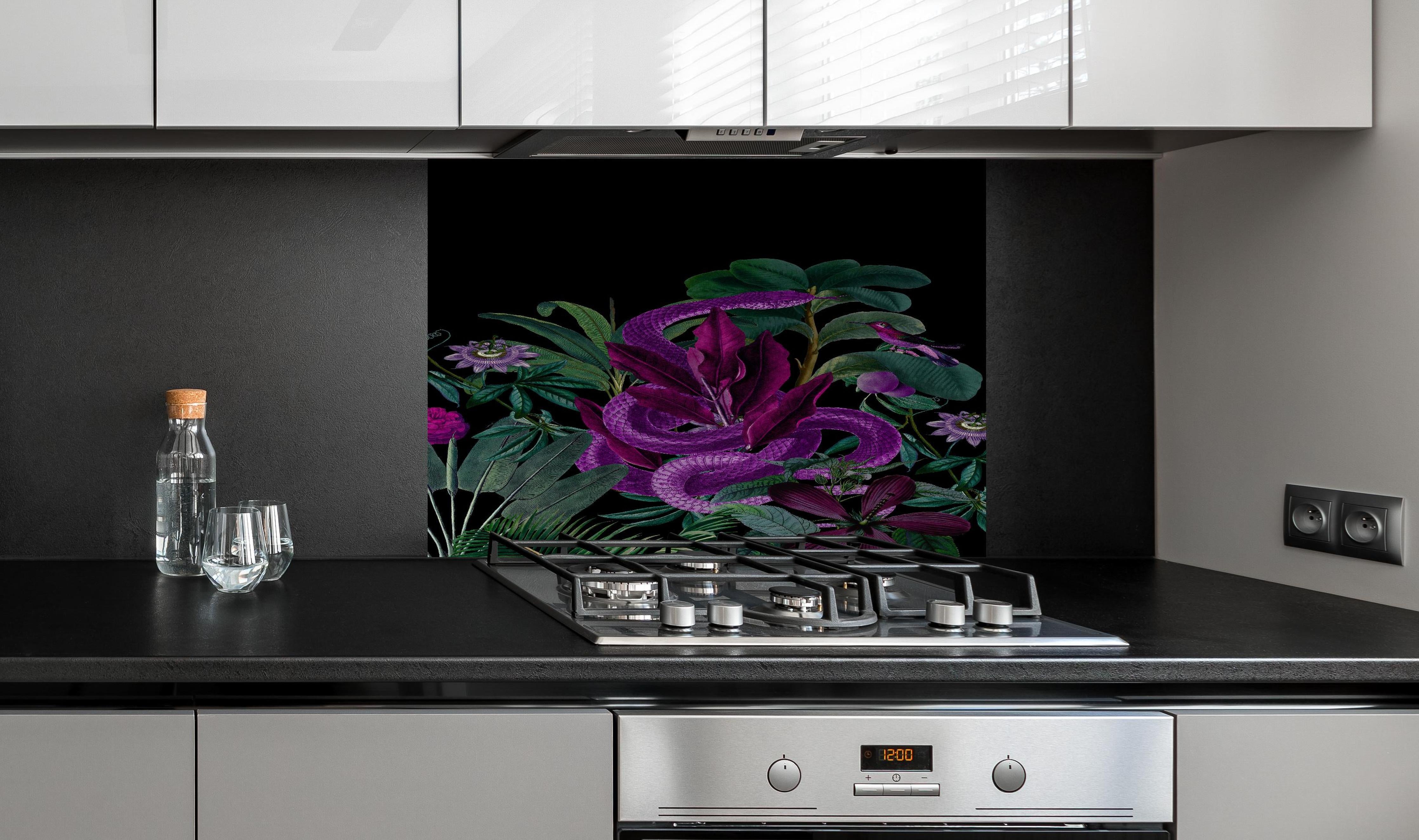 Spritzschutz - Exotischer Schlangenprint in Lila und Grün hinter einem Cerankochfeld zwischen Holz-Kochutensilien