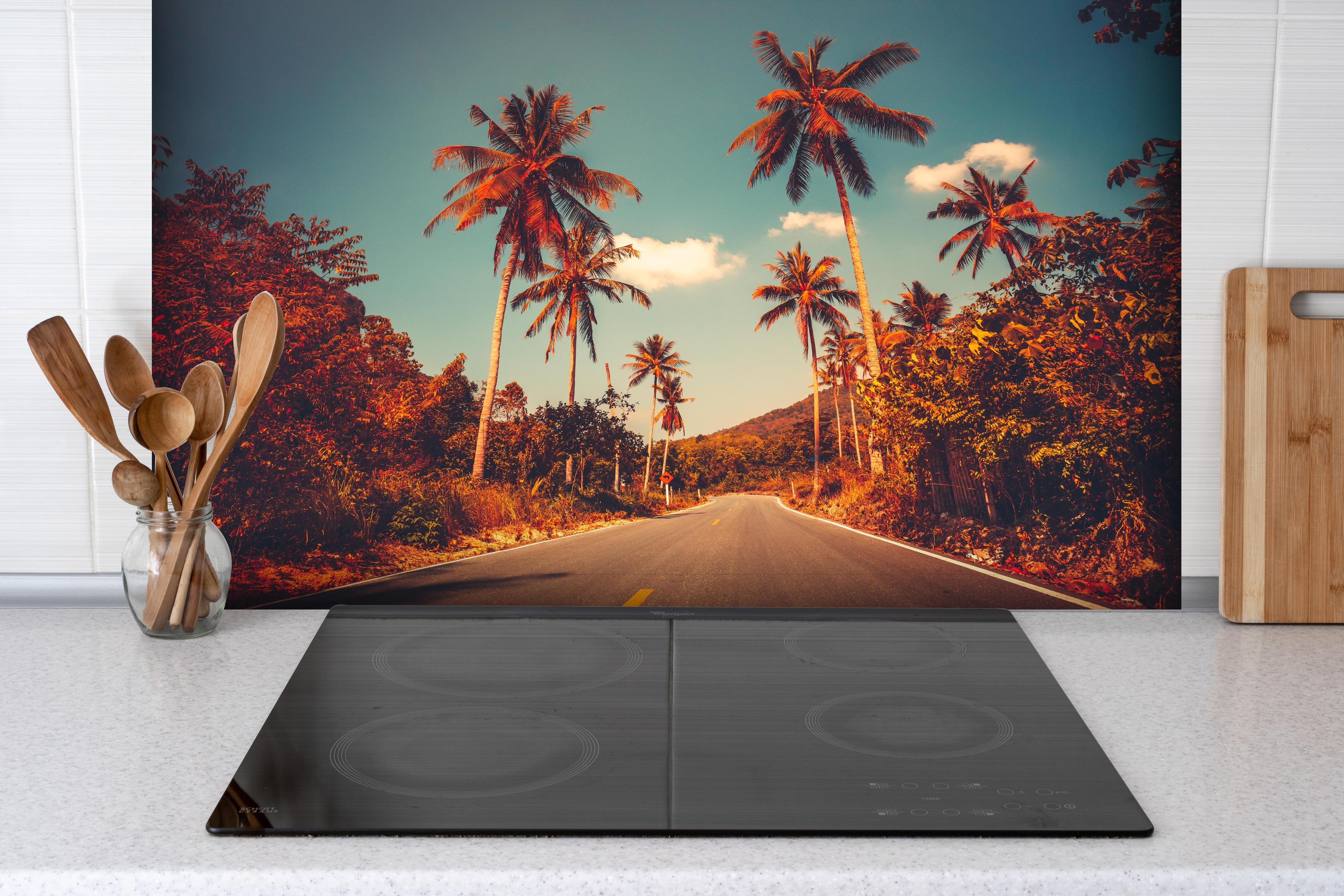 Spritzschutz - Exotischer Sonnenuntergang Palmenlandschaft Bild hinter einem Cerankochfeld zwischen Holz-Kochutensilien