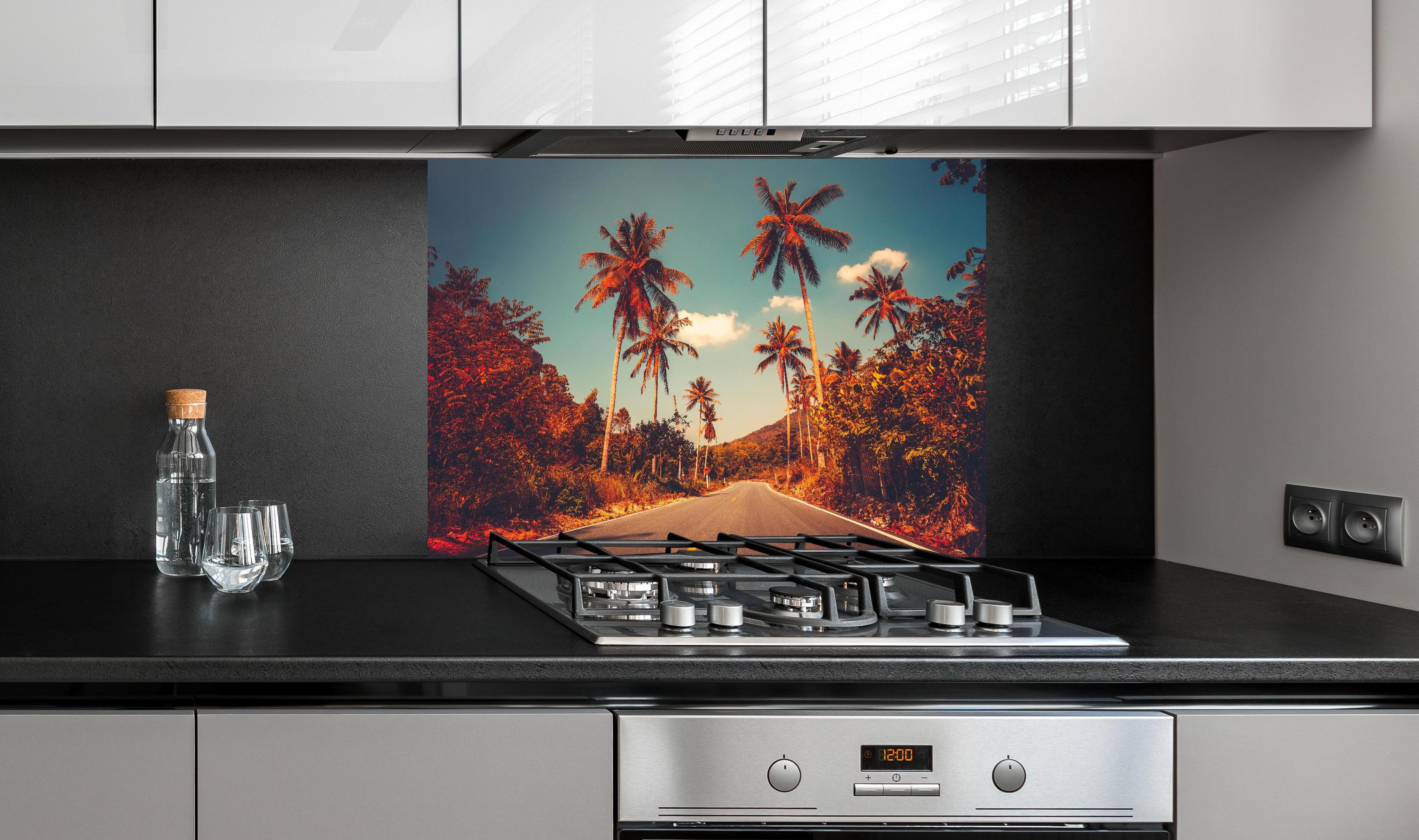 Spritzschutz - Exotischer Sonnenuntergang Palmenlandschaft Bild hinter einem Cerankochfeld zwischen Holz-Kochutensilien