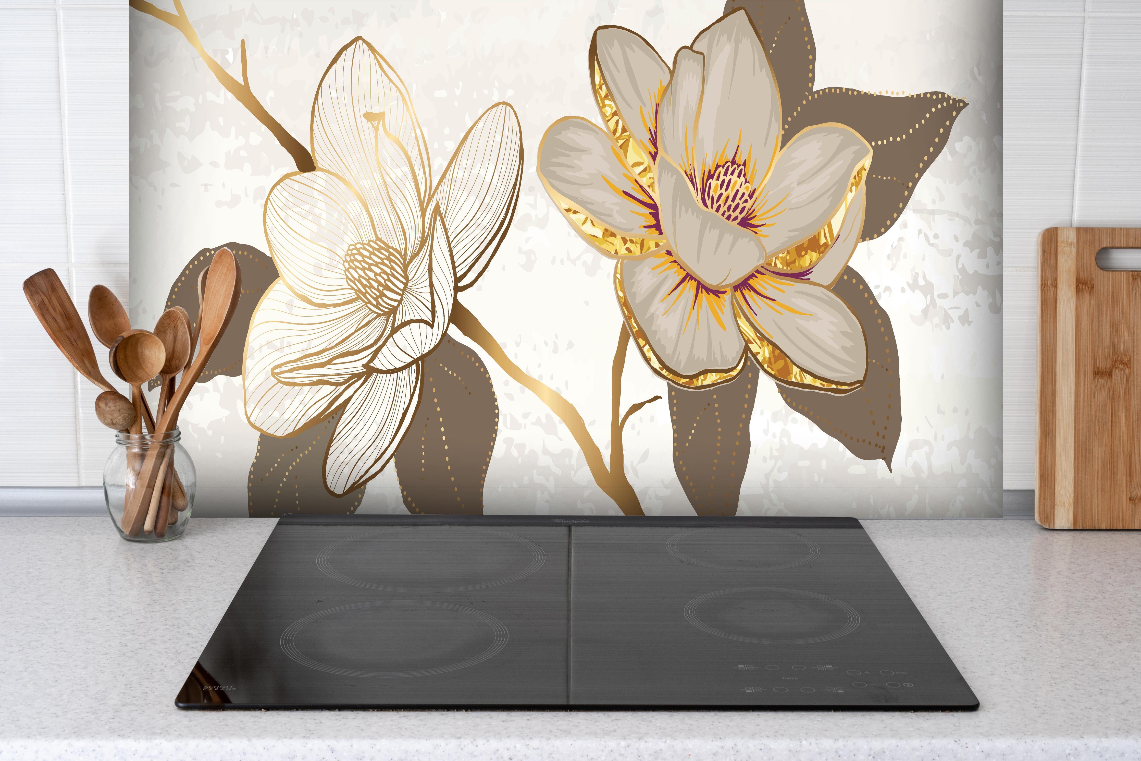 Spritzschutz - Exquisites Magnolienmuster in Gold und Beige hinter einem Cerankochfeld zwischen Holz-Kochutensilien