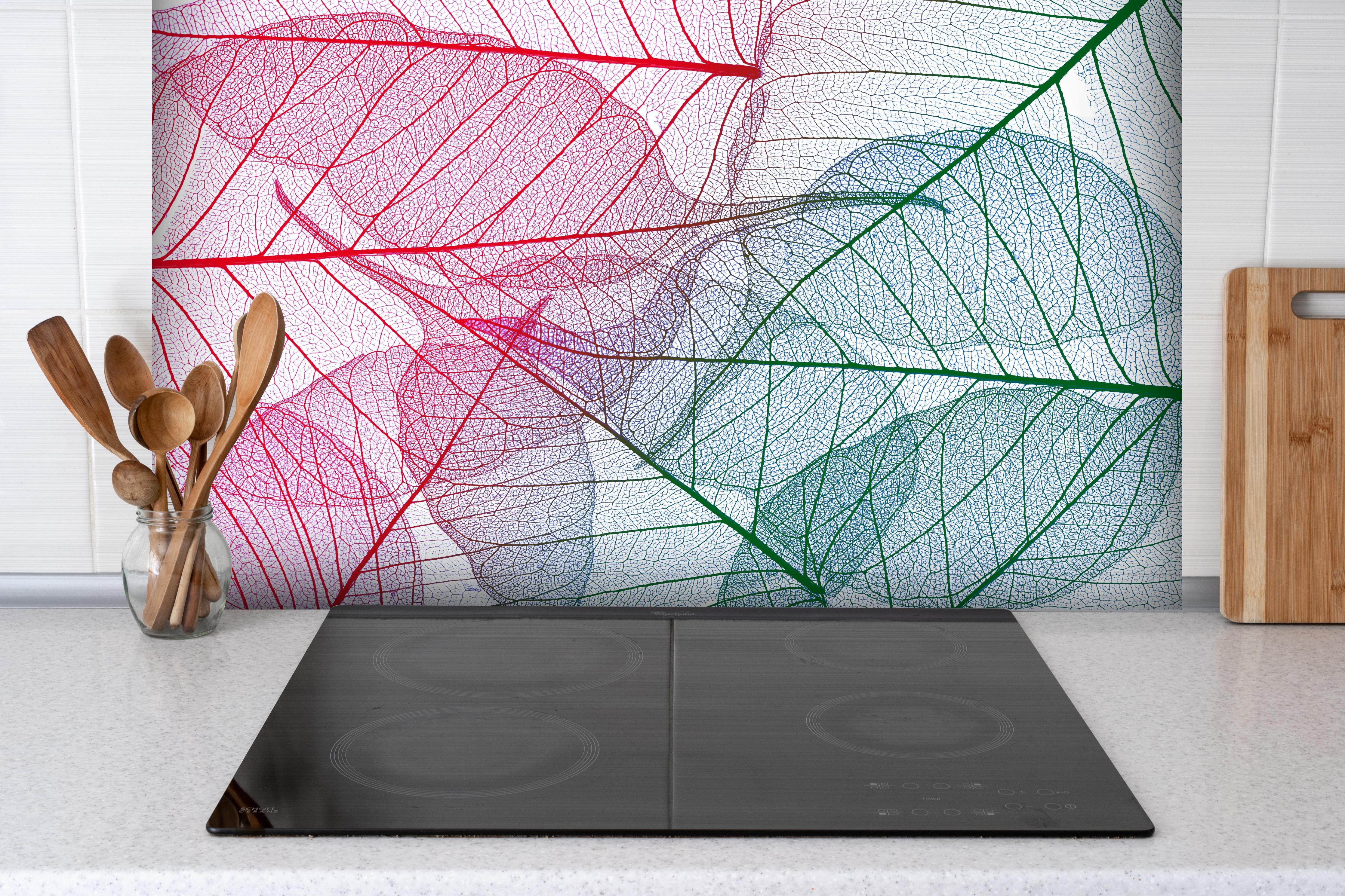 Spritzschutz - Farbenfrohe Blattadern auf Weißem Hintergrund hinter einem Cerankochfeld zwischen Holz-Kochutensilien