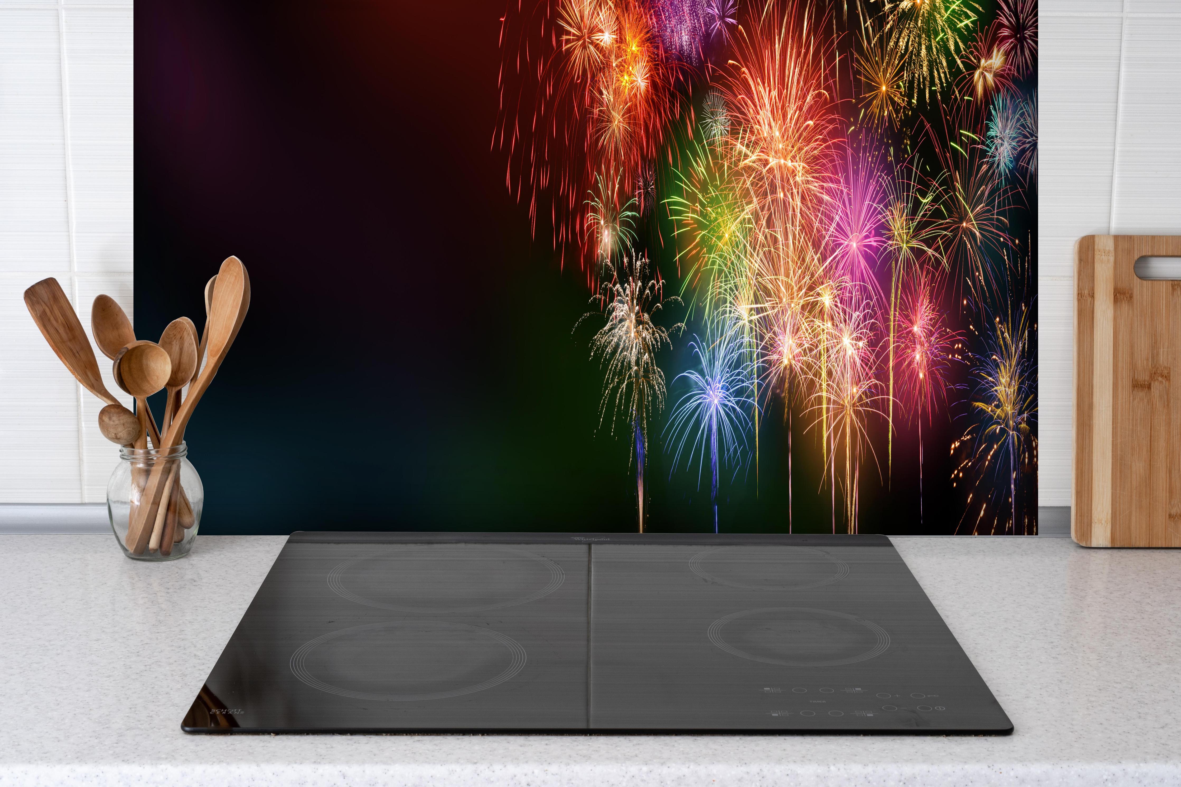 Spritzschutz - Farbenfrohe Feuerwerk-Show am Nachthimmel hinter einem Cerankochfeld zwischen Holz-Kochutensilien