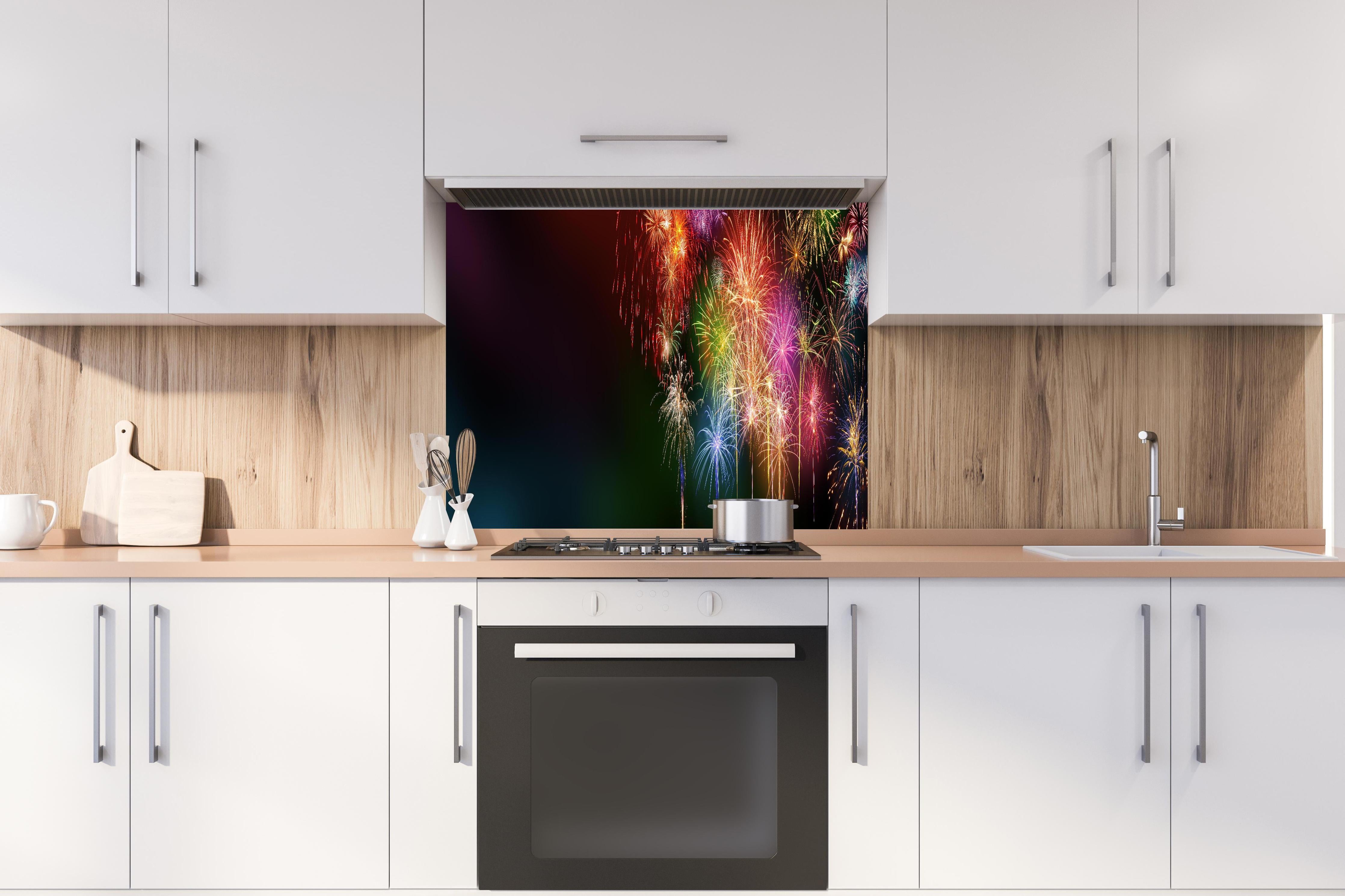 Spritzschutz - Farbenfrohe Feuerwerk-Show am Nachthimmel hinter einem Cerankochfeld zwischen Holz-Kochutensilien