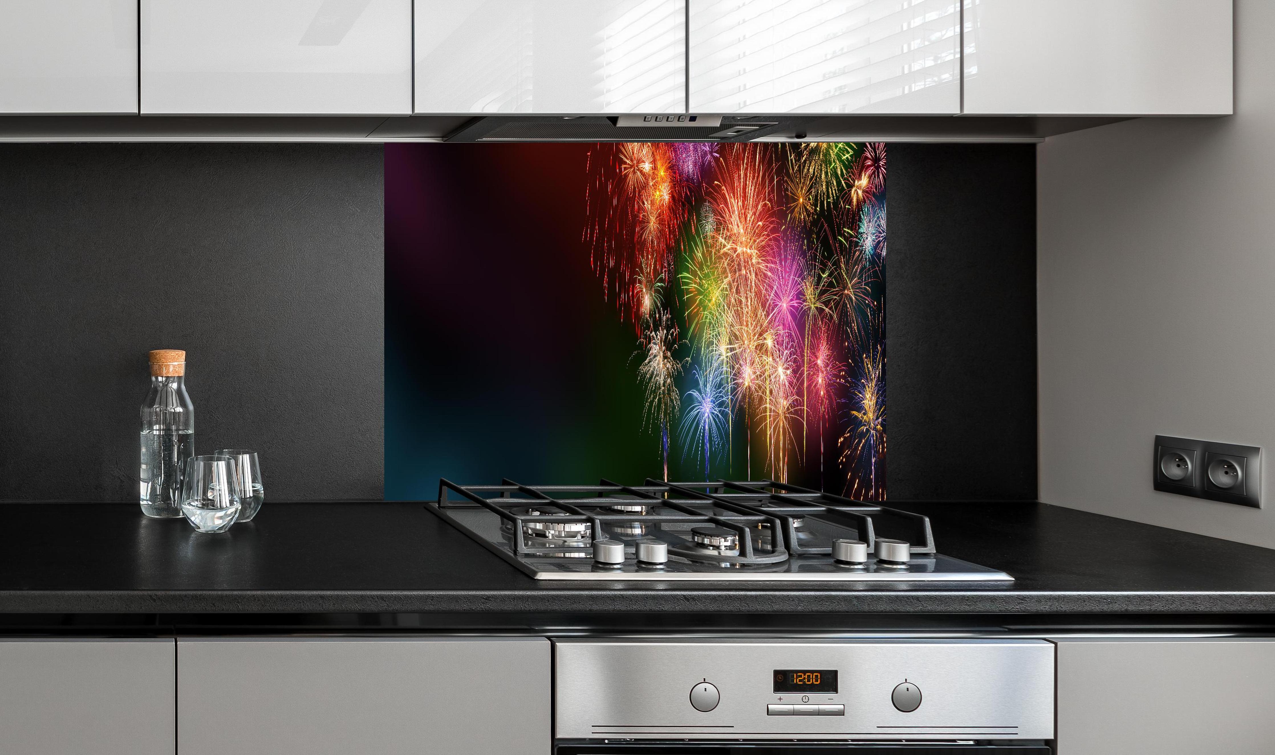 Spritzschutz - Farbenfrohe Feuerwerk-Show am Nachthimmel hinter einem Cerankochfeld zwischen Holz-Kochutensilien