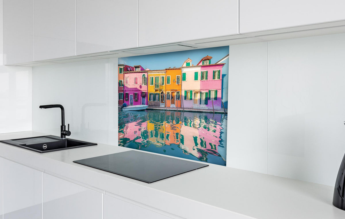 Spritzschutz - Farbenfrohe Häuser am Wasser in Burano, Venedig hinter einem Cerankochfeld zwischen Holz-Kochutensilien