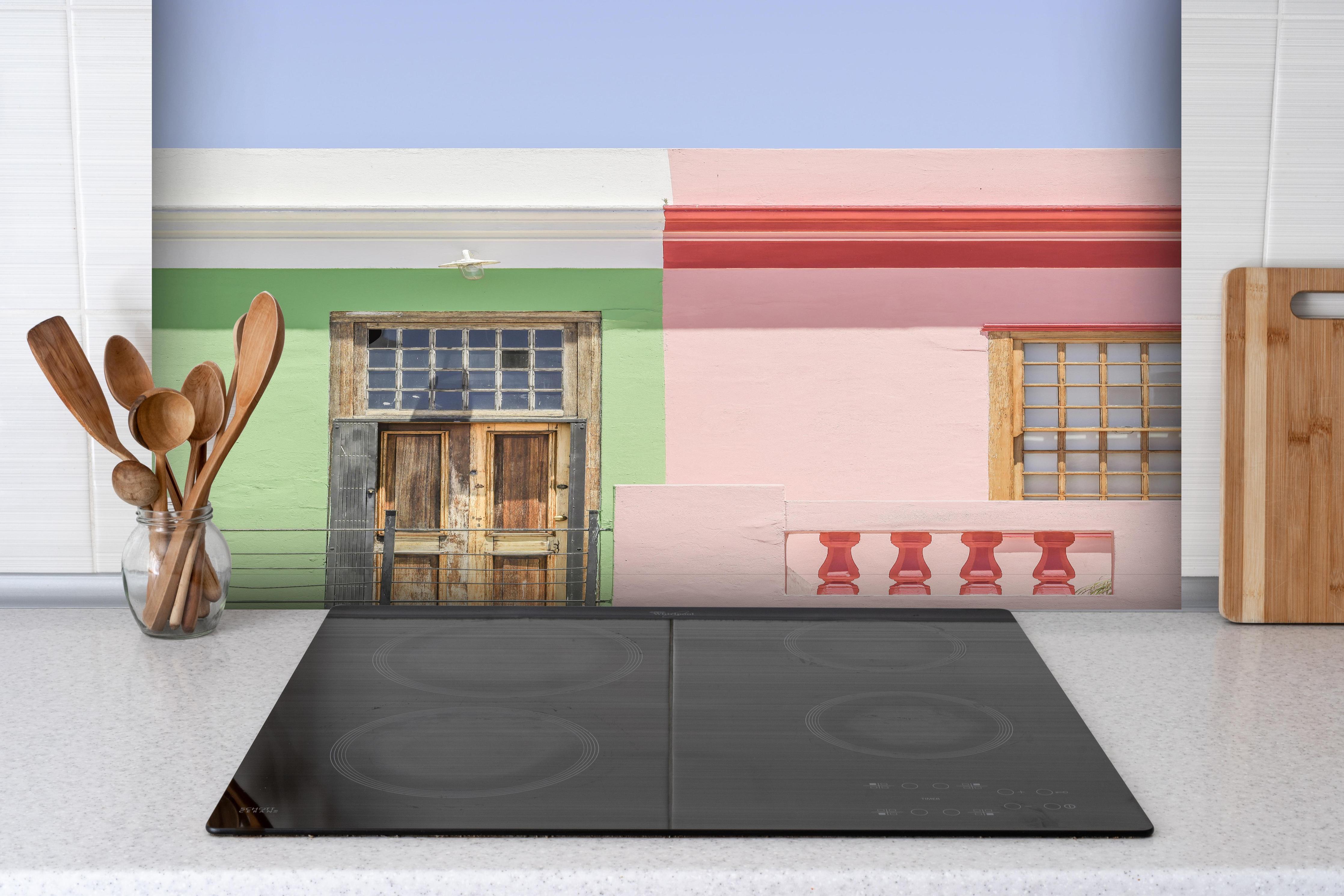 Spritzschutz - Farbenfrohe Stadthaus Fassaden im Sonnenlicht hinter einem Cerankochfeld zwischen Holz-Kochutensilien