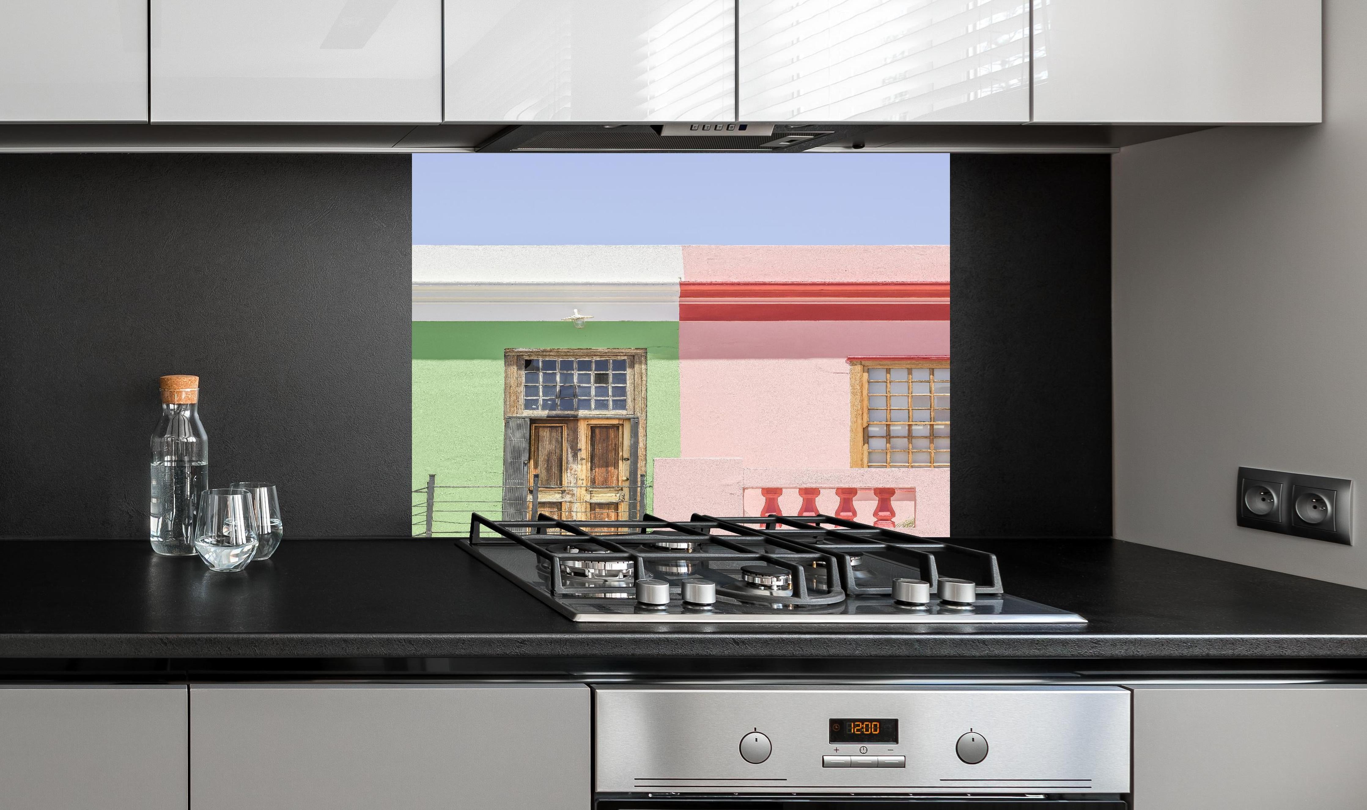 Spritzschutz - Farbenfrohe Stadthaus Fassaden im Sonnenlicht hinter einem Cerankochfeld zwischen Holz-Kochutensilien