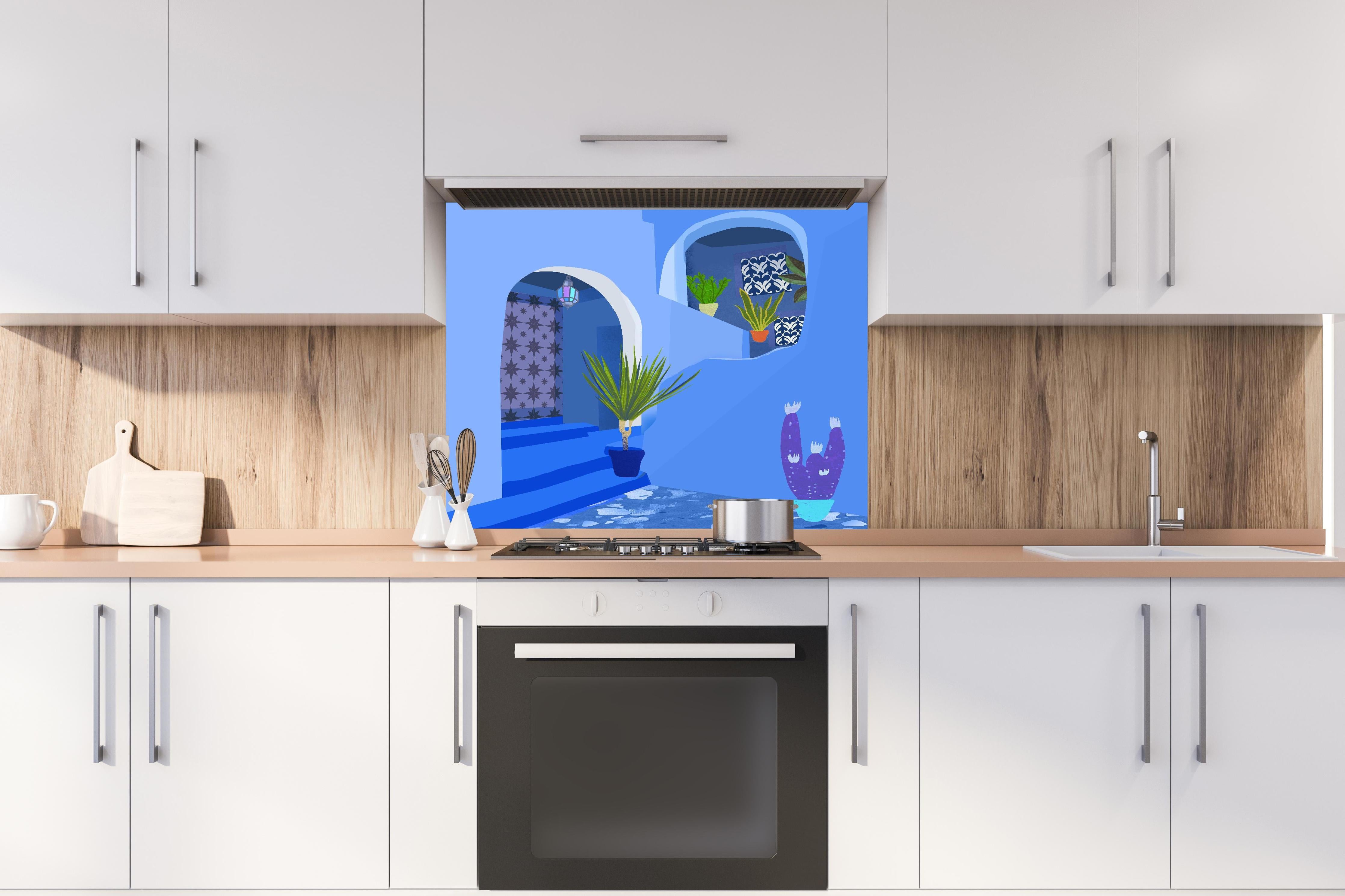 Spritzschutz - Farbenfrohes Architekturposter Marokko hinter einem Cerankochfeld zwischen Holz-Kochutensilien