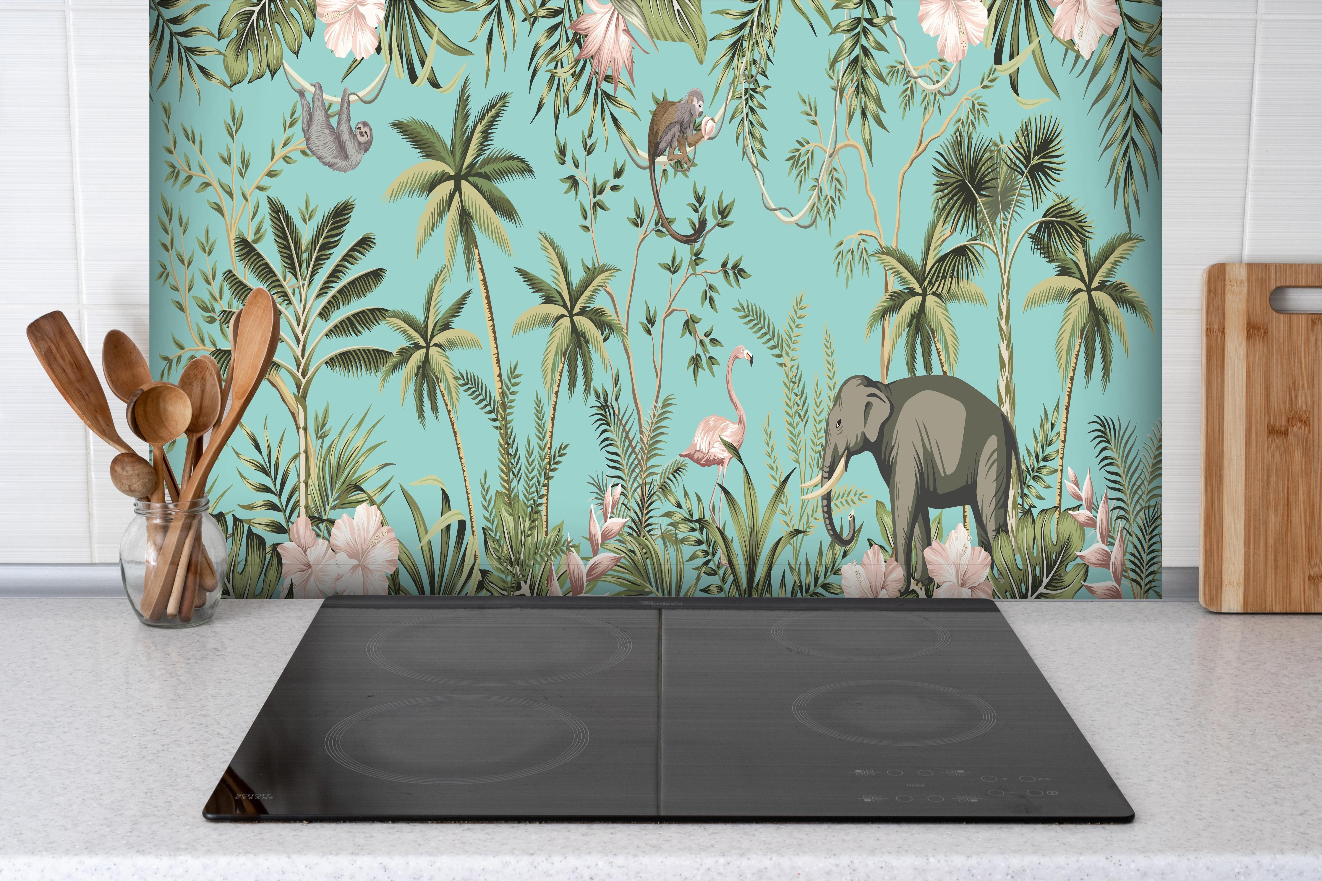 Spritzschutz - Farbenfrohes Dschungel-Muster auf Textil hinter einem Cerankochfeld zwischen Holz-Kochutensilien