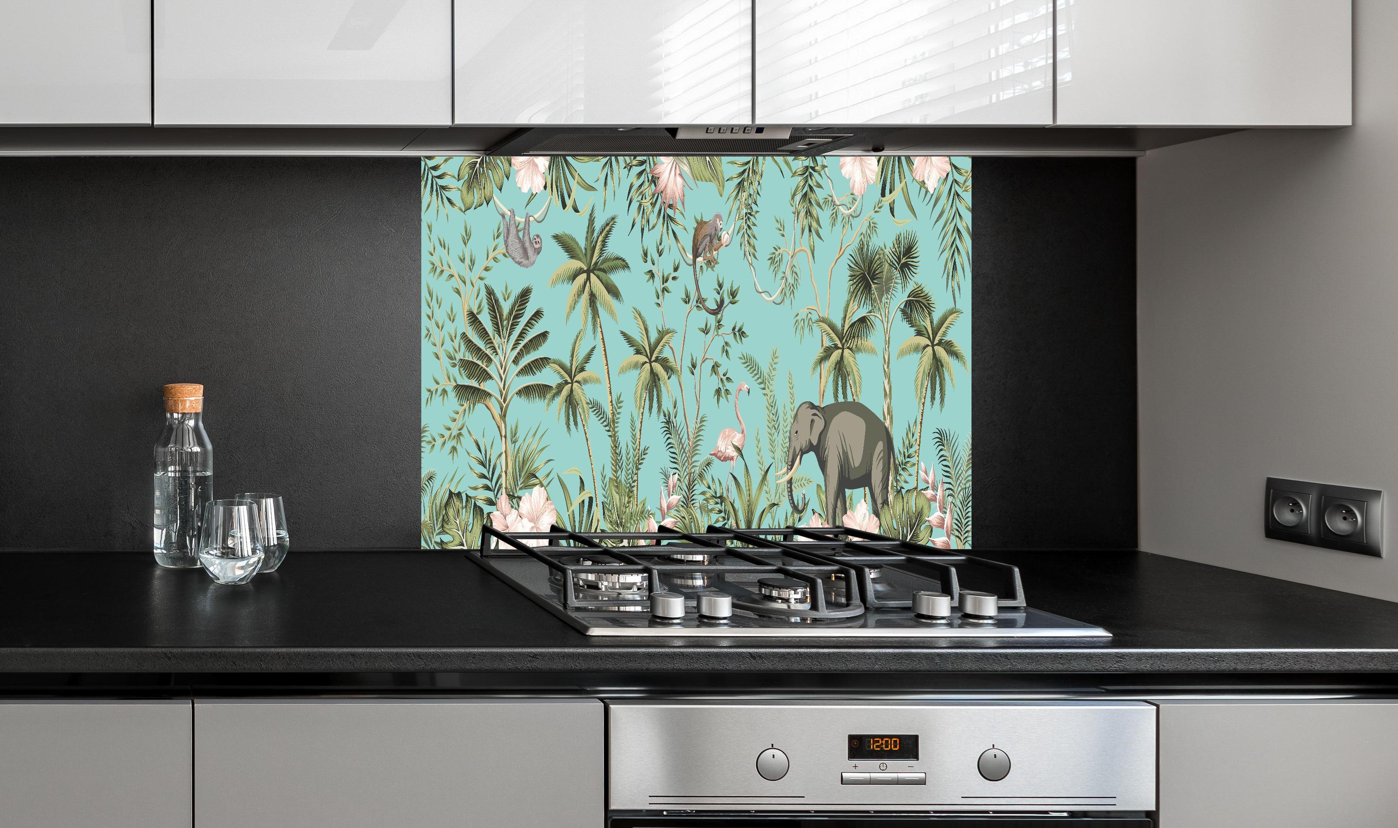 Spritzschutz - Farbenfrohes Dschungel-Muster auf Textil hinter einem Cerankochfeld zwischen Holz-Kochutensilien