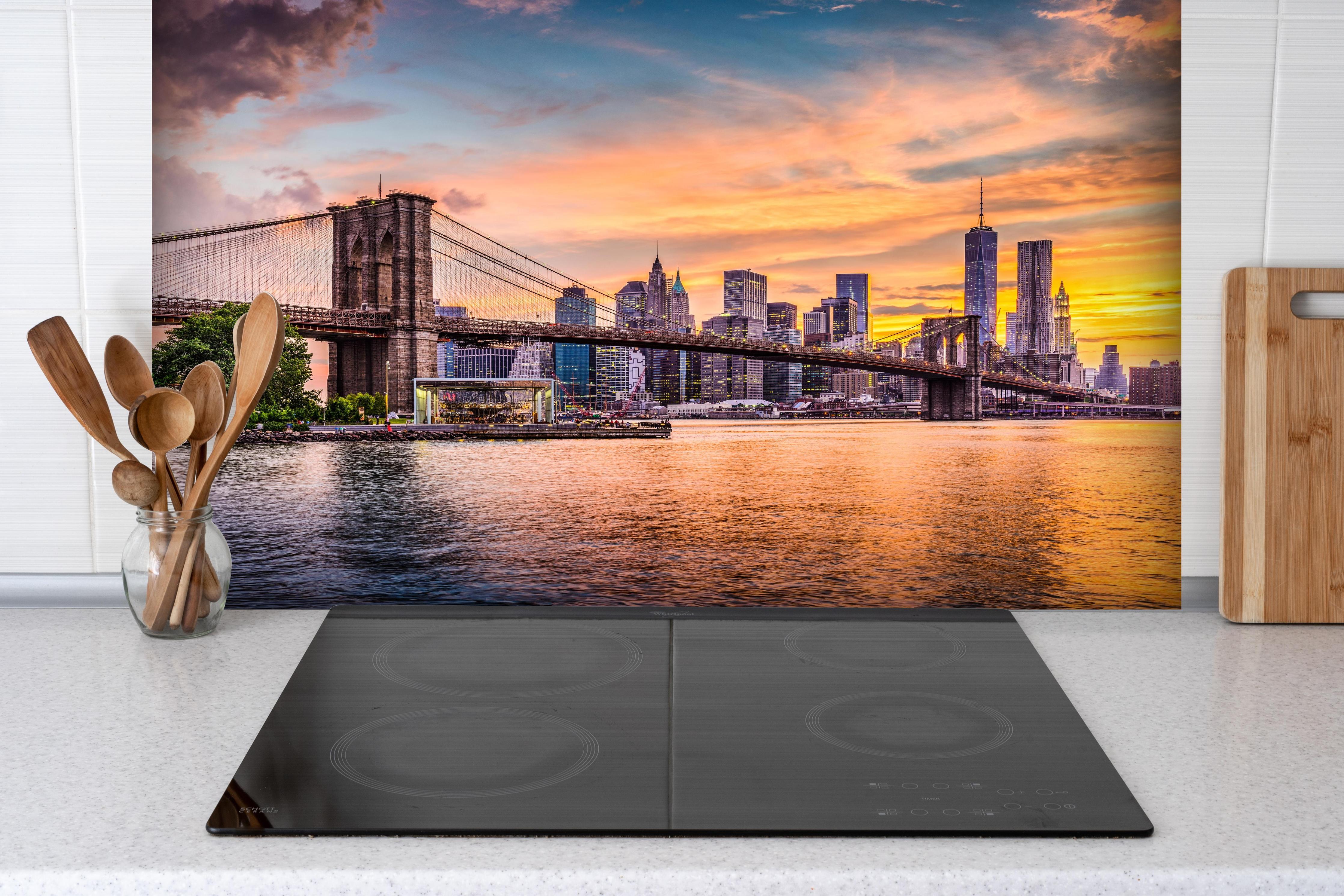 Spritzschutz - Farbenprächtiger Sonnenuntergang über New York hinter einem Cerankochfeld zwischen Holz-Kochutensilien