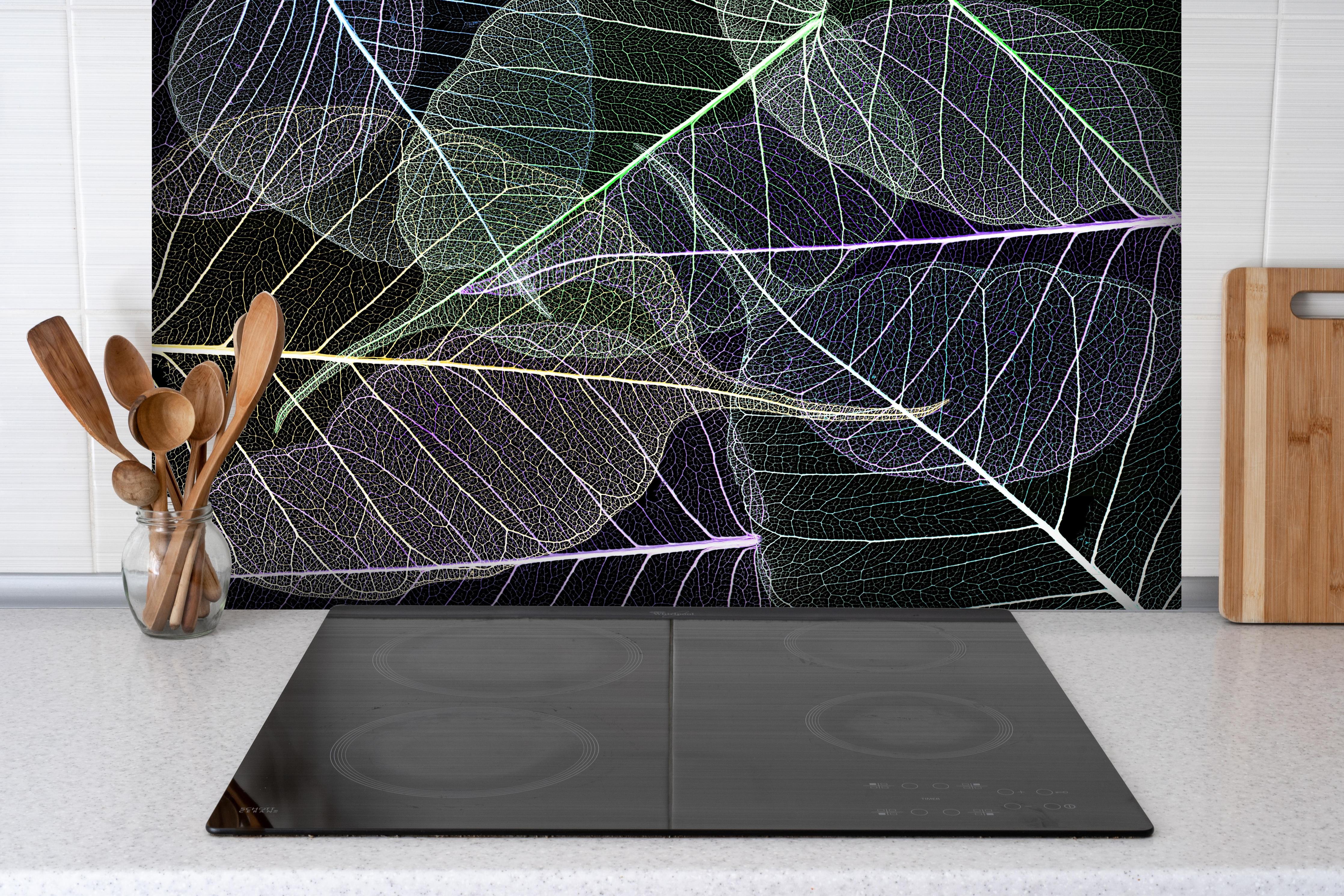 Spritzschutz - Farbige Texturierung von Laub auf Schwarzem Hintergrund hinter einem Cerankochfeld zwischen Holz-Kochutensilien
