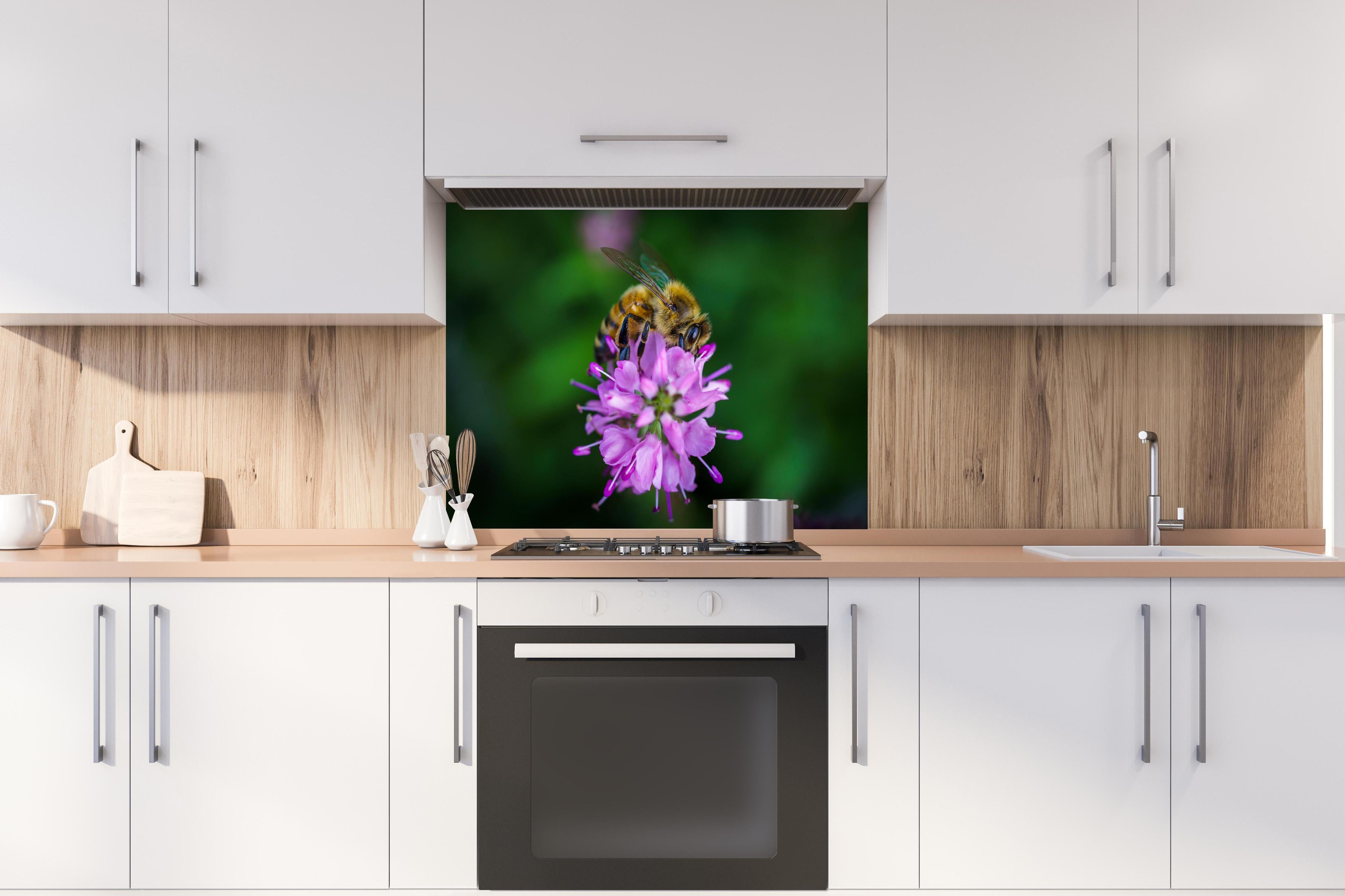 Spritzschutz - Faszinierende Biene auf lebendiger lila Blüte hinter einem Cerankochfeld zwischen Holz-Kochutensilien