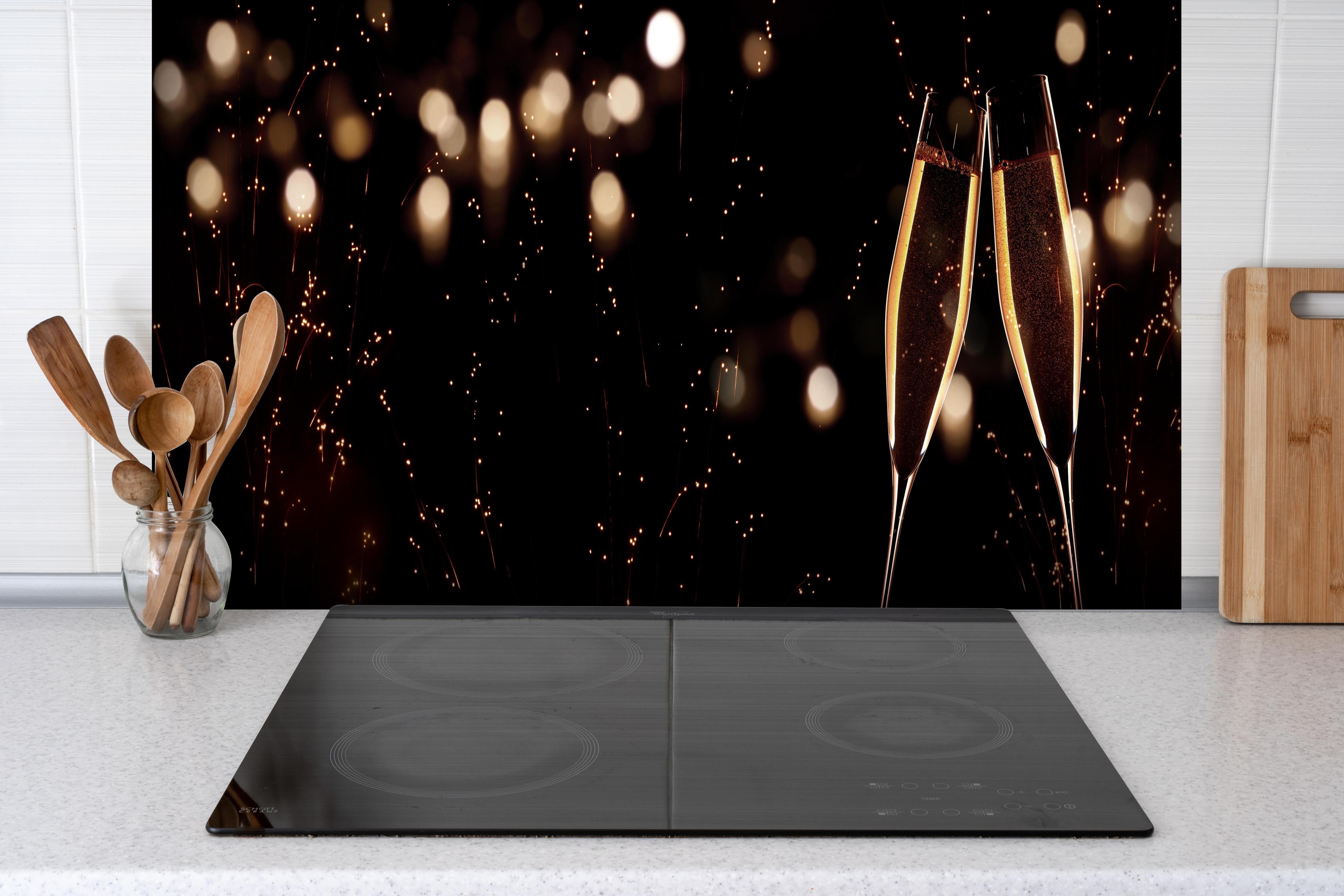 Spritzschutz - Feierlicher Champagner-Clink bei Jahreswechsel hinter einem Cerankochfeld zwischen Holz-Kochutensilien