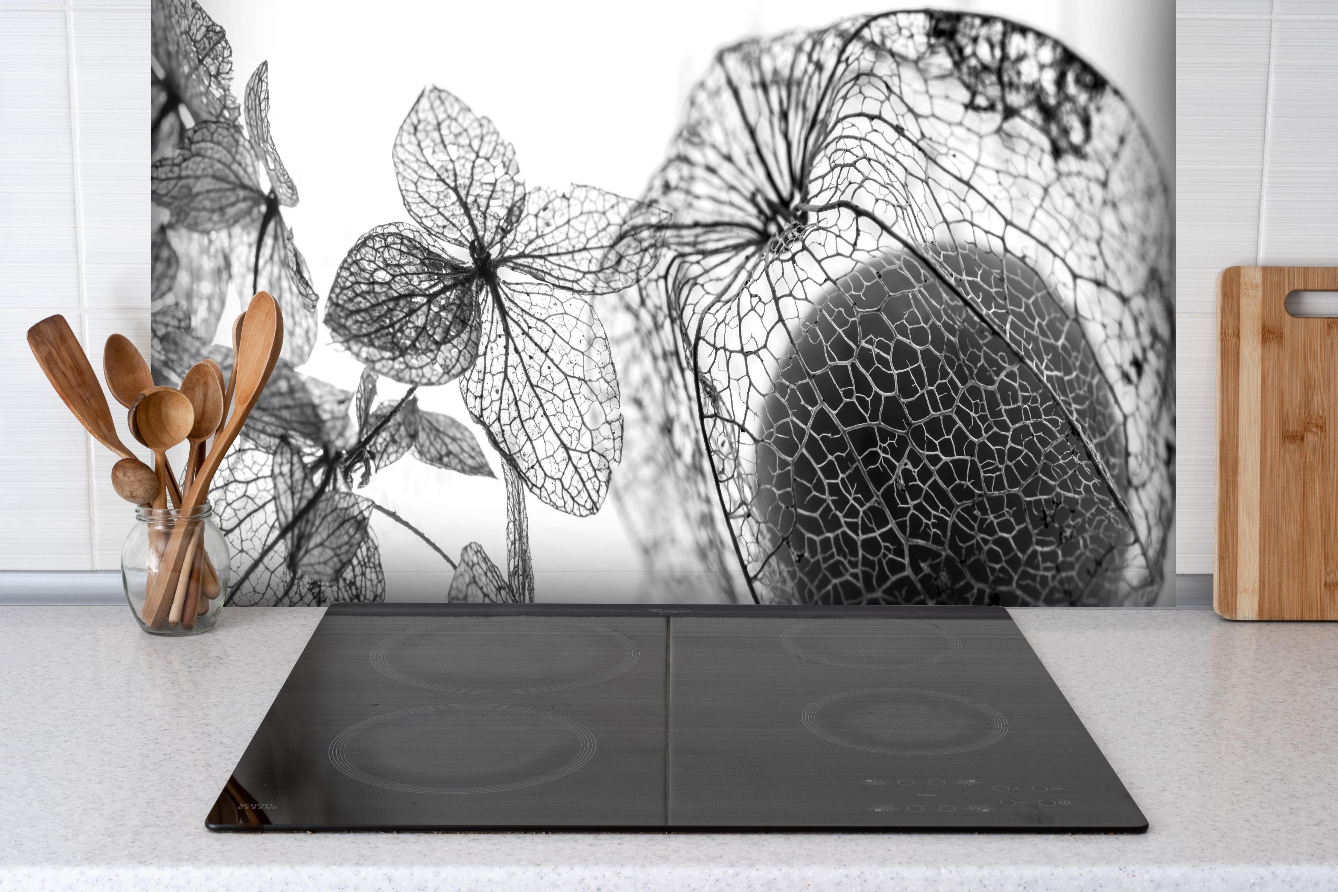 Spritzschutz - Feine Herbstlaub-Struktur in Weiß-Grau hinter einem Cerankochfeld zwischen Holz-Kochutensilien