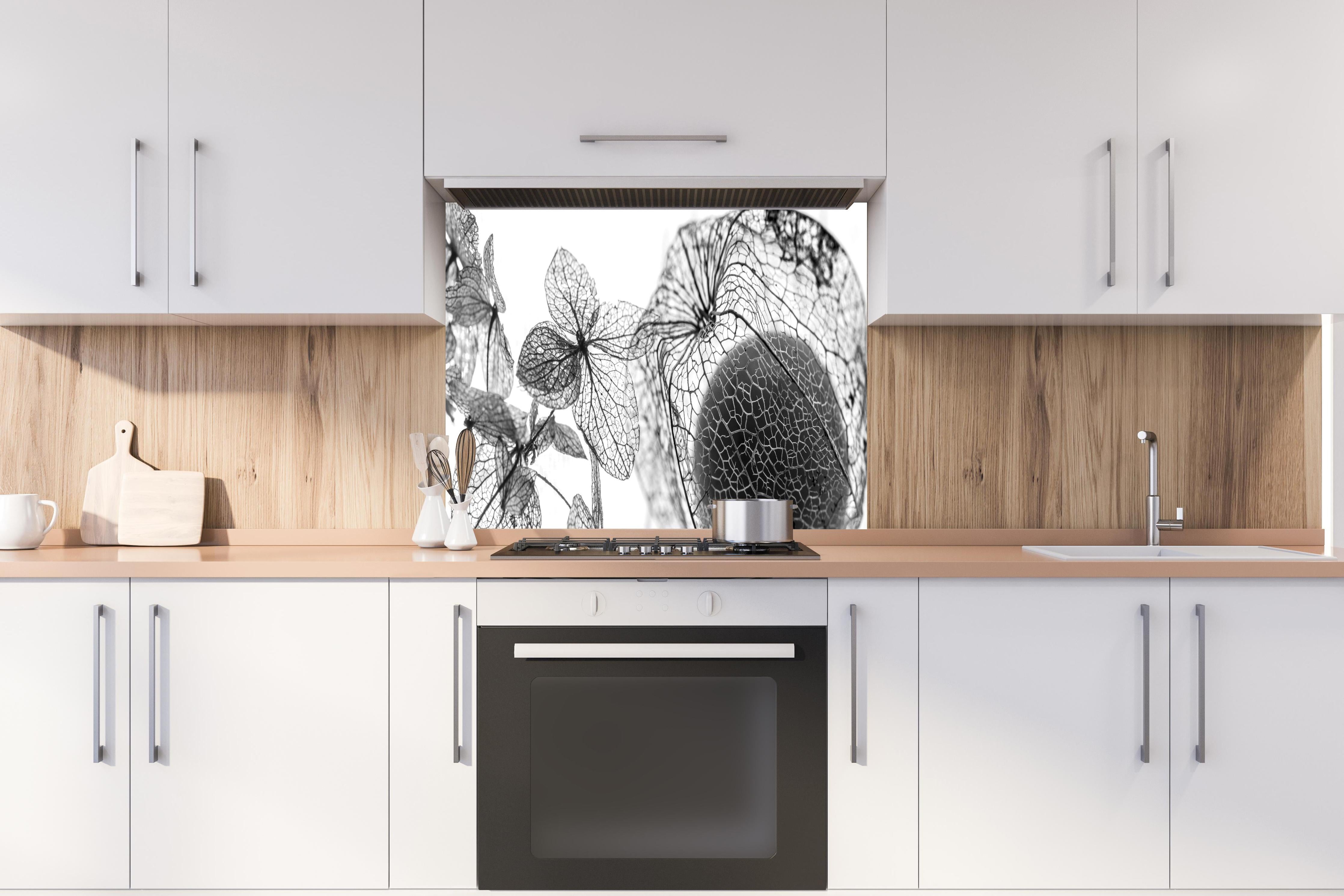 Spritzschutz - Feine Herbstlaub-Struktur in Weiß-Grau hinter einem Cerankochfeld zwischen Holz-Kochutensilien