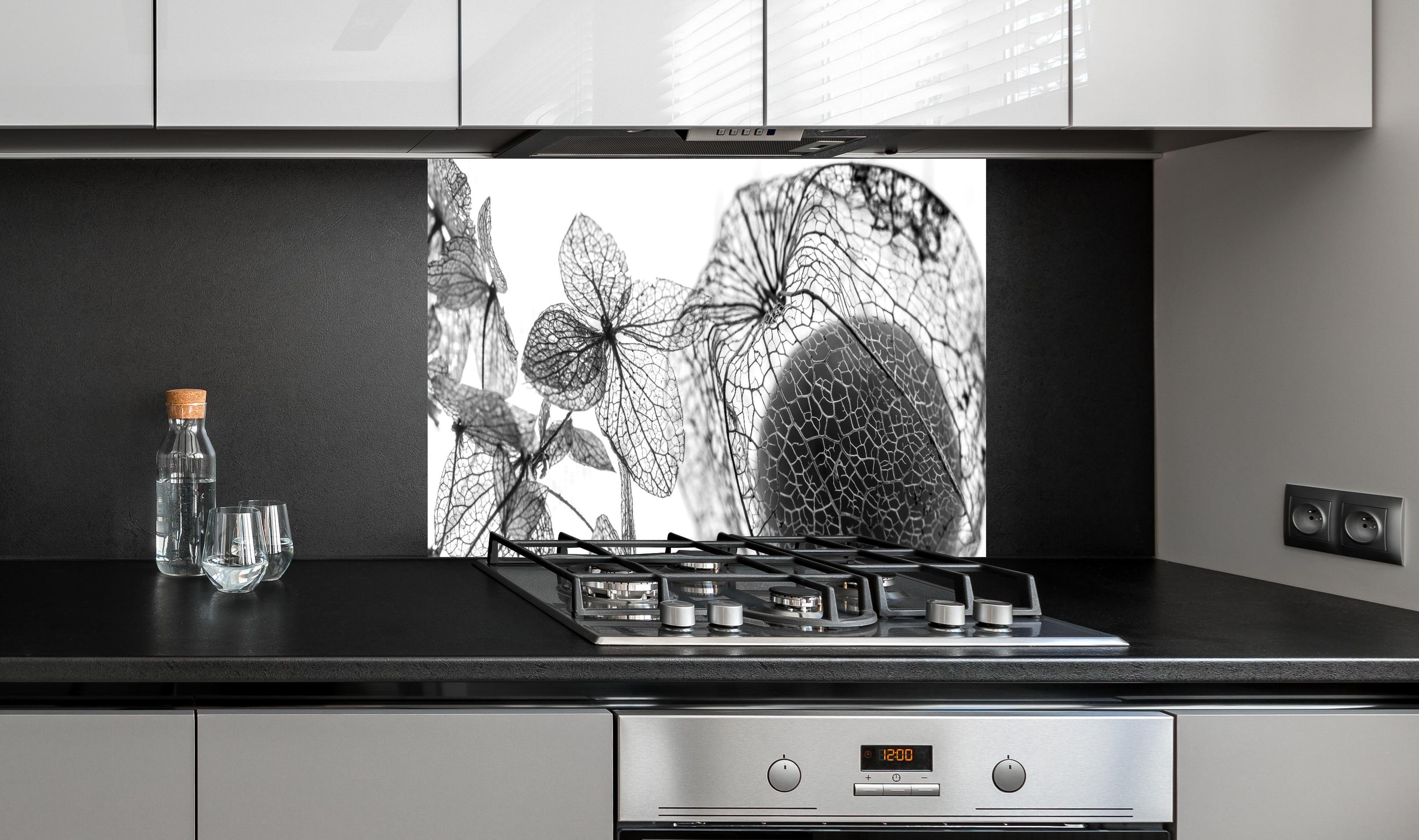 Spritzschutz - Feine Herbstlaub-Struktur in Weiß-Grau hinter einem Cerankochfeld zwischen Holz-Kochutensilien