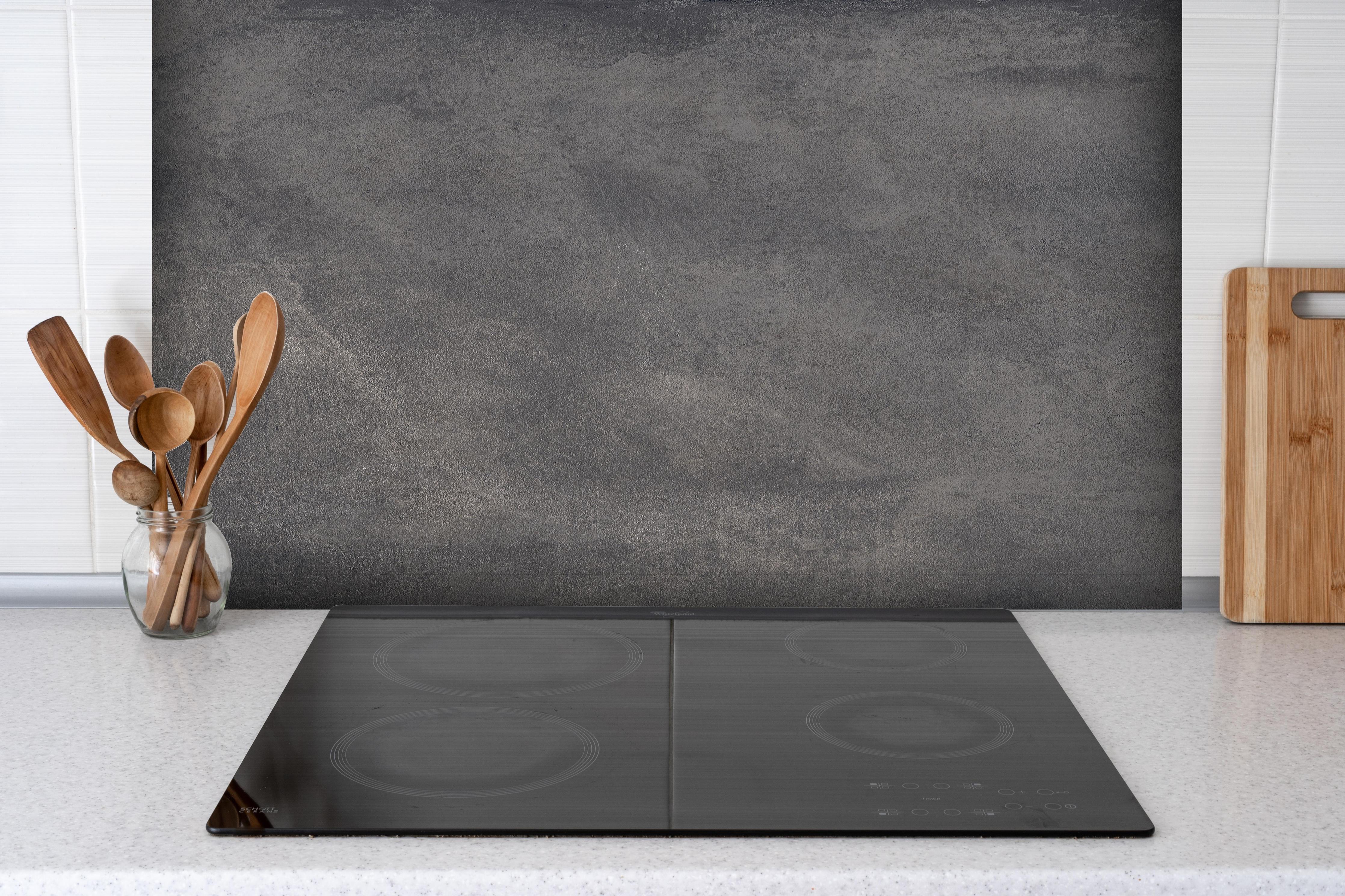 Spritzschutz - Feine dunkle Betonwand hinter einem Cerankochfeld zwischen Holz-Kochutensilien