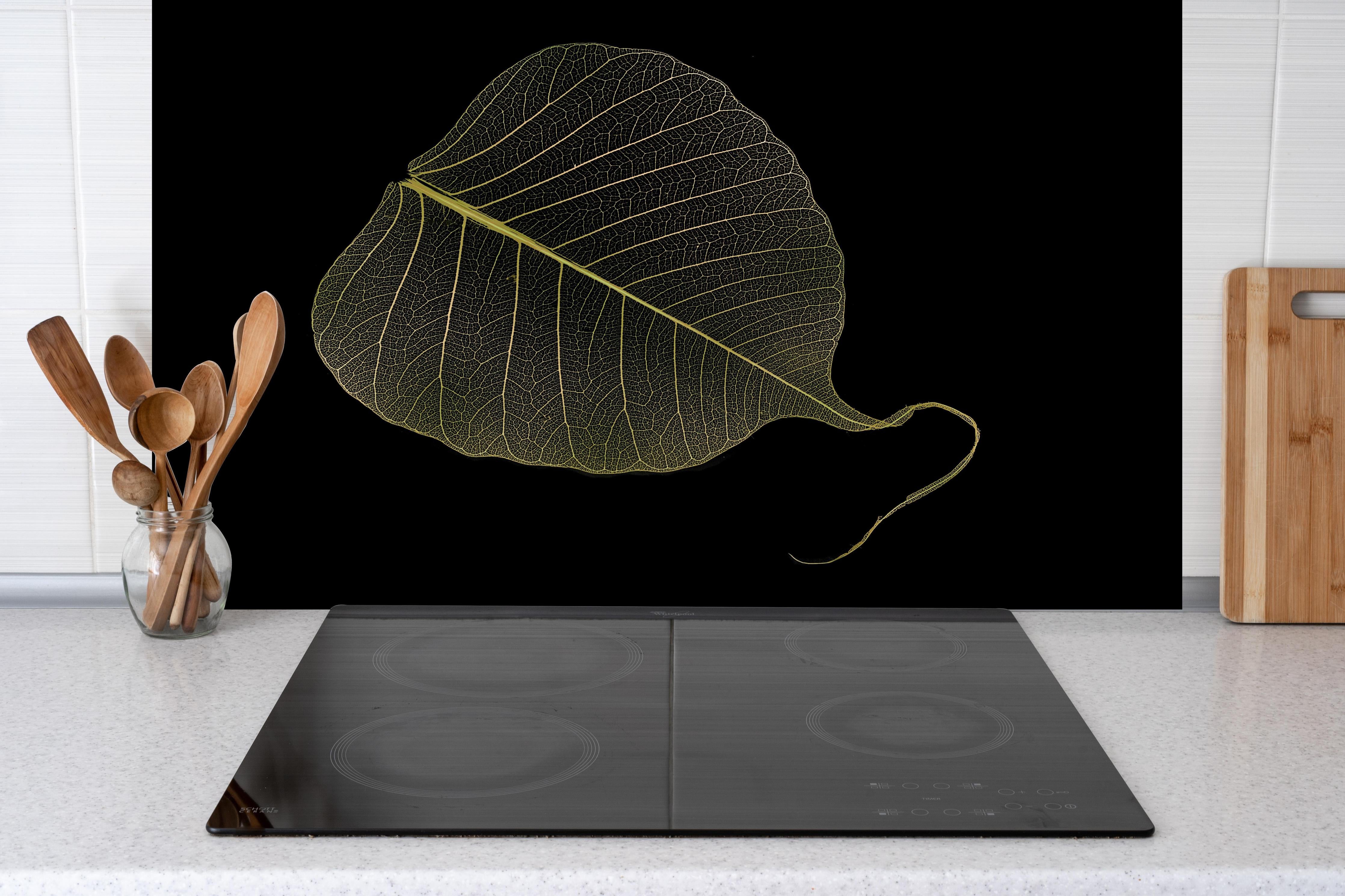 Spritzschutz - Feine gelbe Blattadern Schwarz Hintergrund hinter einem Cerankochfeld zwischen Holz-Kochutensilien