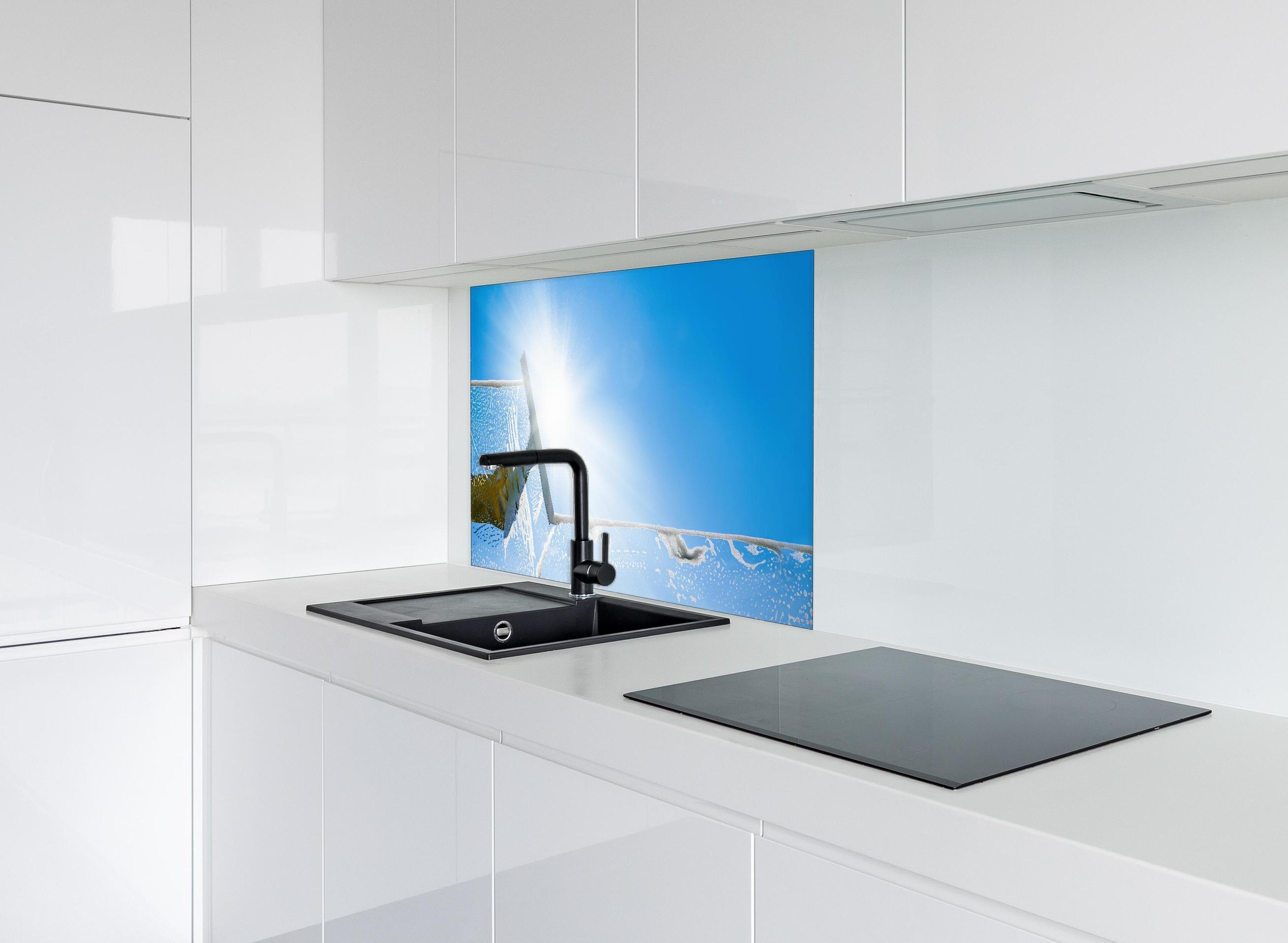 Spritzschutz - Fensterputzer mit Abzieher und strahlendem Himmel hinter einem Cerankochfeld zwischen Holz-Kochutensilien