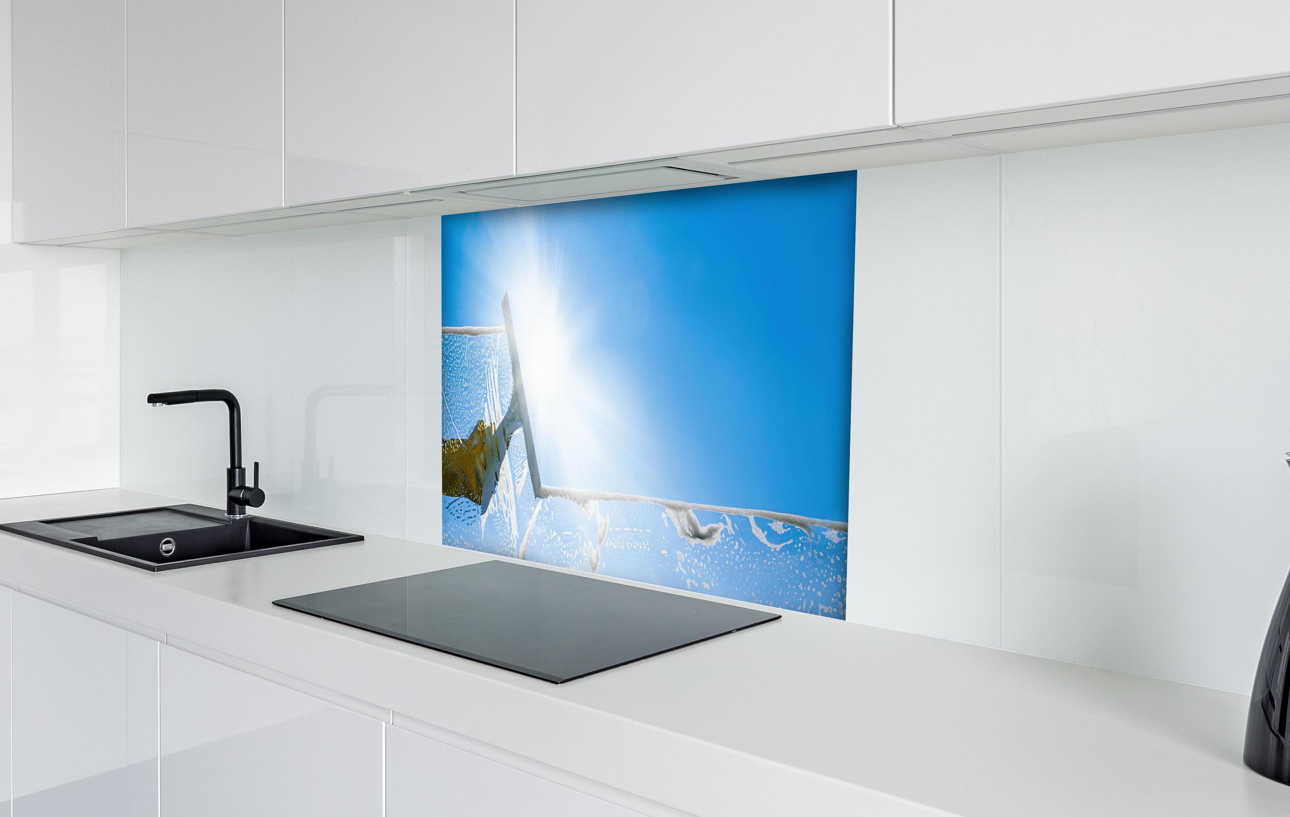 Spritzschutz - Fensterputzer mit Abzieher und strahlendem Himmel hinter einem Cerankochfeld zwischen Holz-Kochutensilien