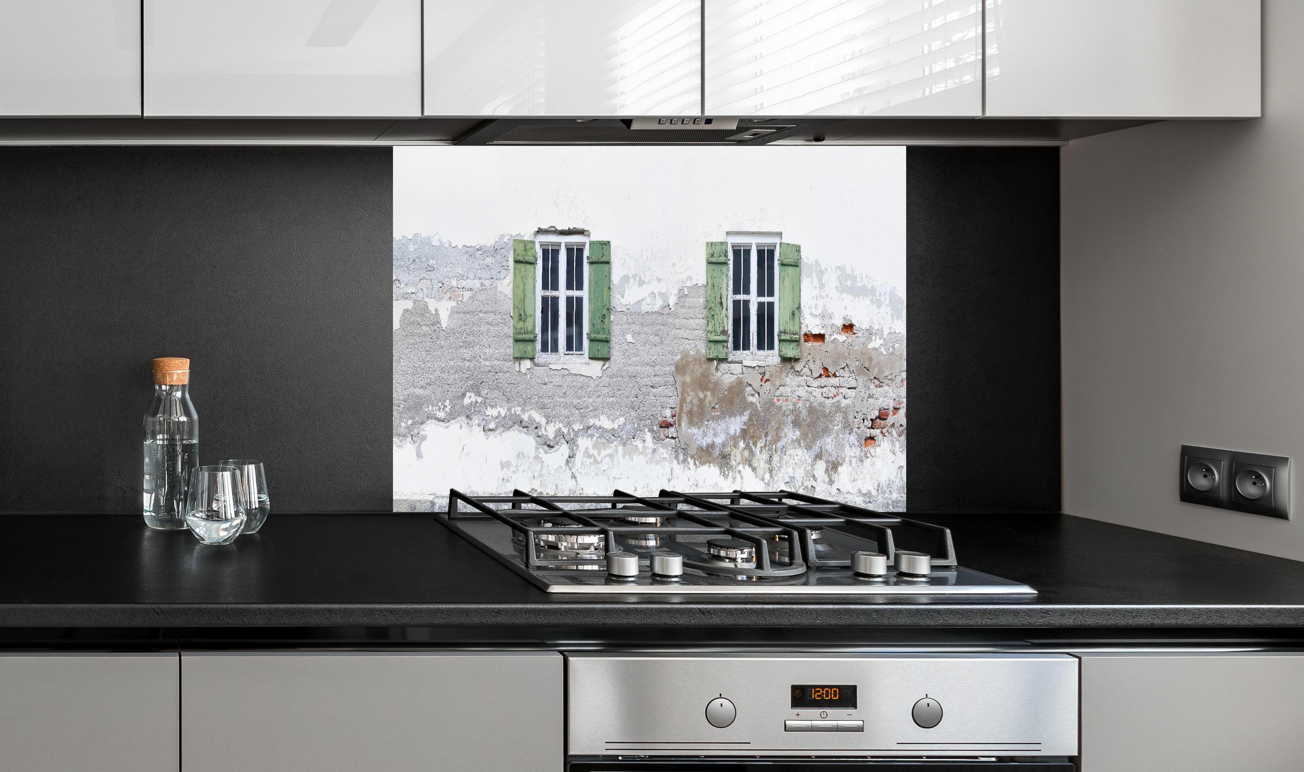 Spritzschutz - Fensterrahmen einer veralteten Hauswand hinter einem Cerankochfeld zwischen Holz-Kochutensilien