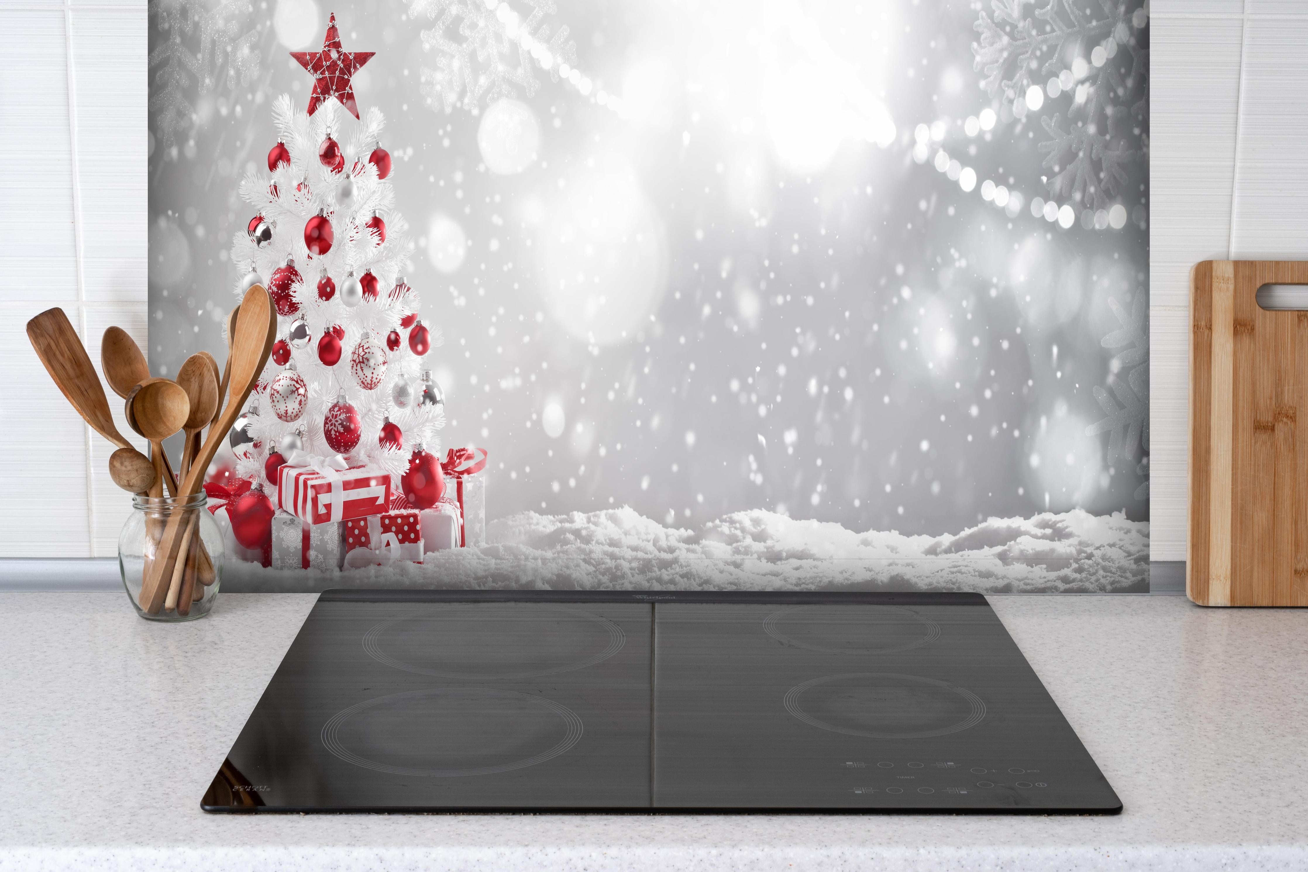 Spritzschutz - Festlicher Weihnachtsbaum mit roten Akzenten hinter einem Cerankochfeld zwischen Holz-Kochutensilien
