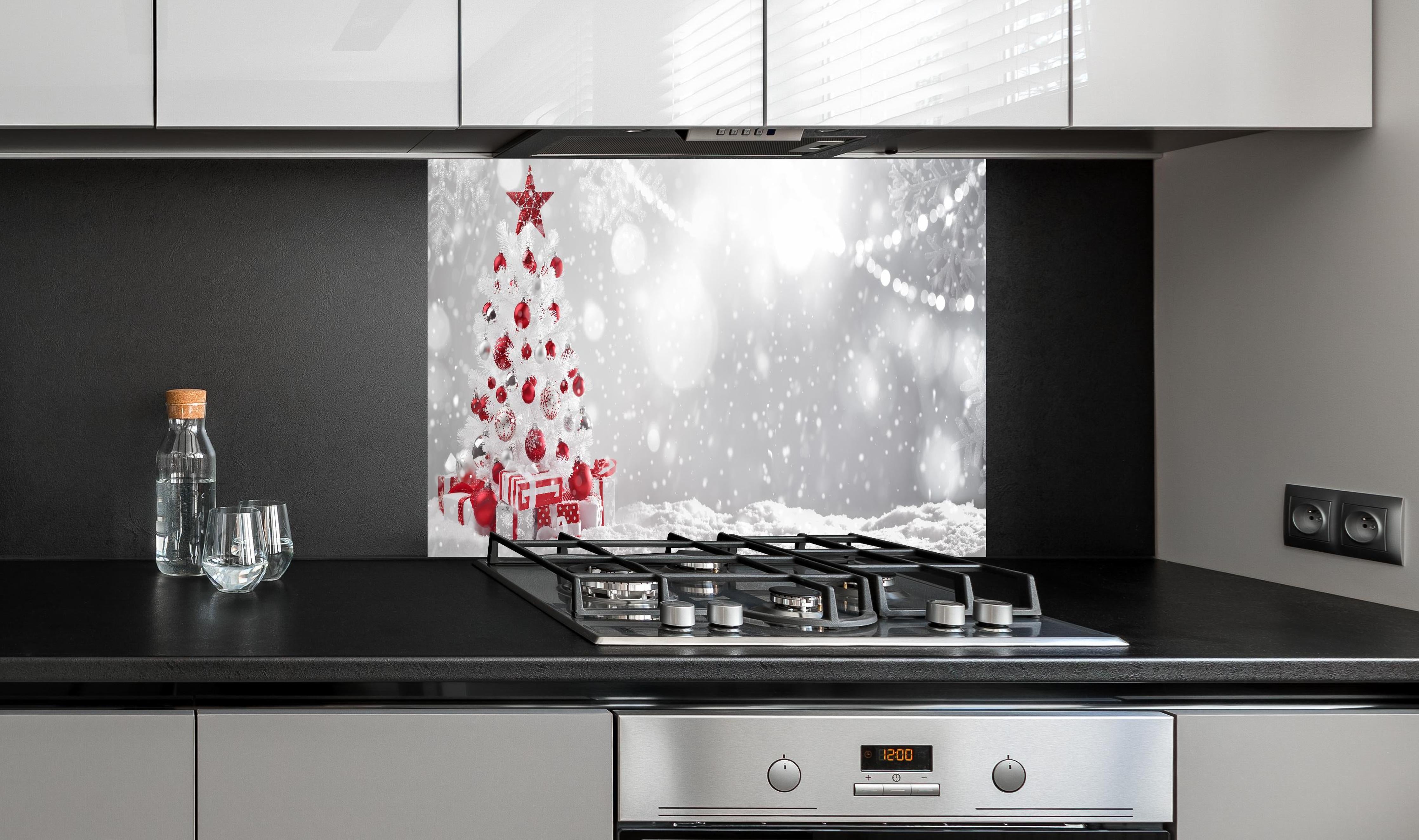 Spritzschutz - Festlicher Weihnachtsbaum mit roten Akzenten hinter einem Cerankochfeld zwischen Holz-Kochutensilien