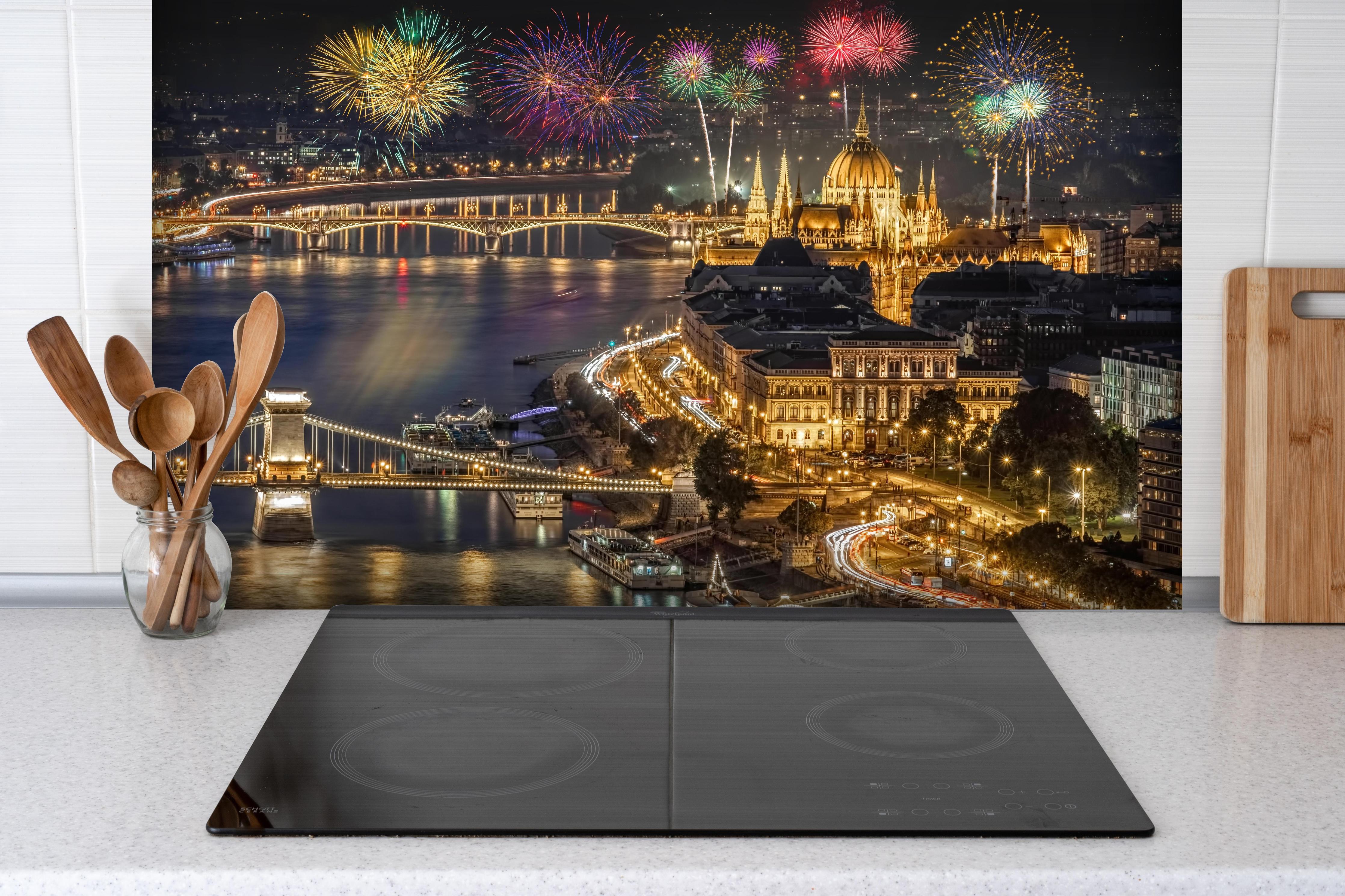Spritzschutz - Feuerwerk über Budapest bei Nacht hinter einem Cerankochfeld zwischen Holz-Kochutensilien