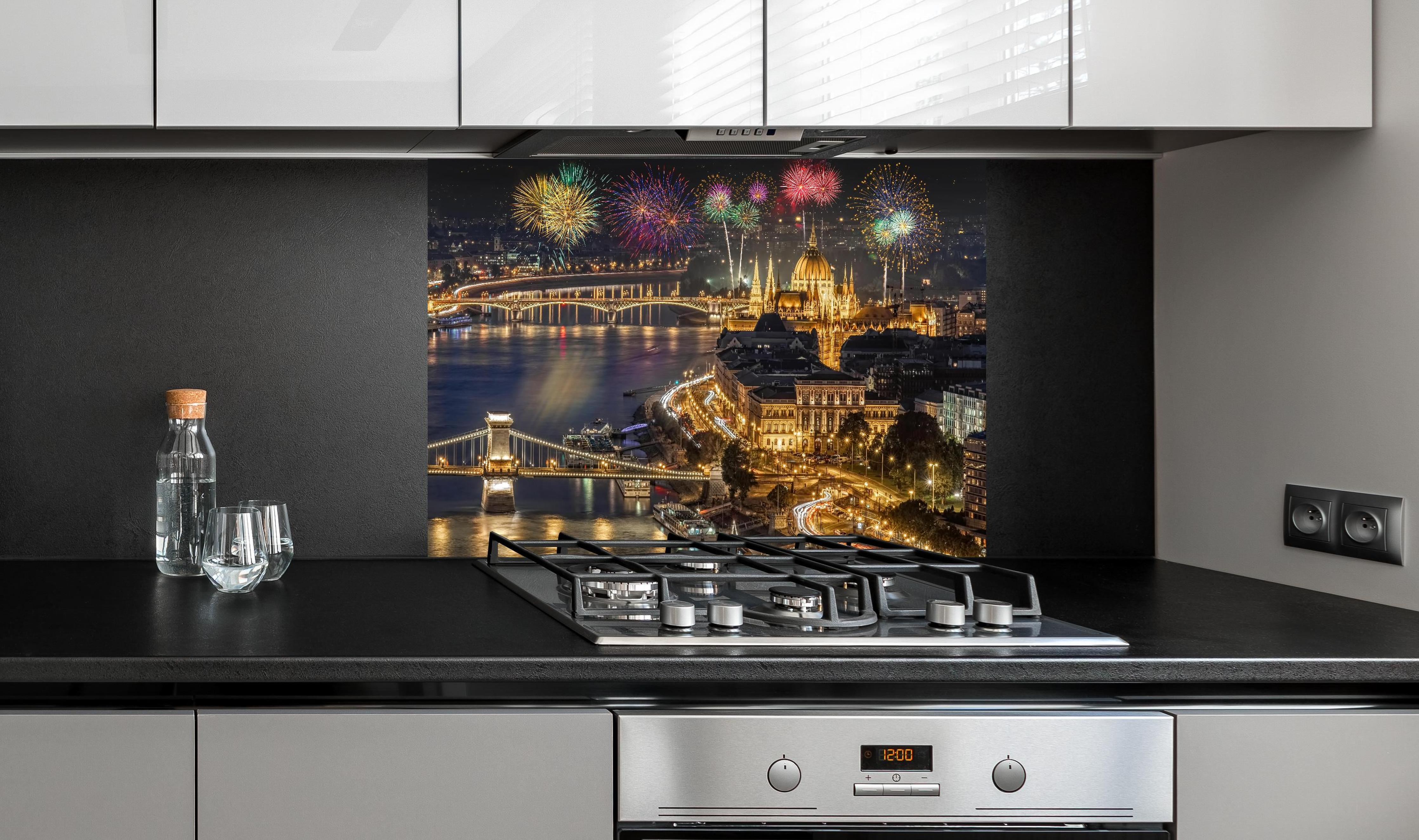 Spritzschutz - Feuerwerk über Budapest bei Nacht hinter einem Cerankochfeld zwischen Holz-Kochutensilien