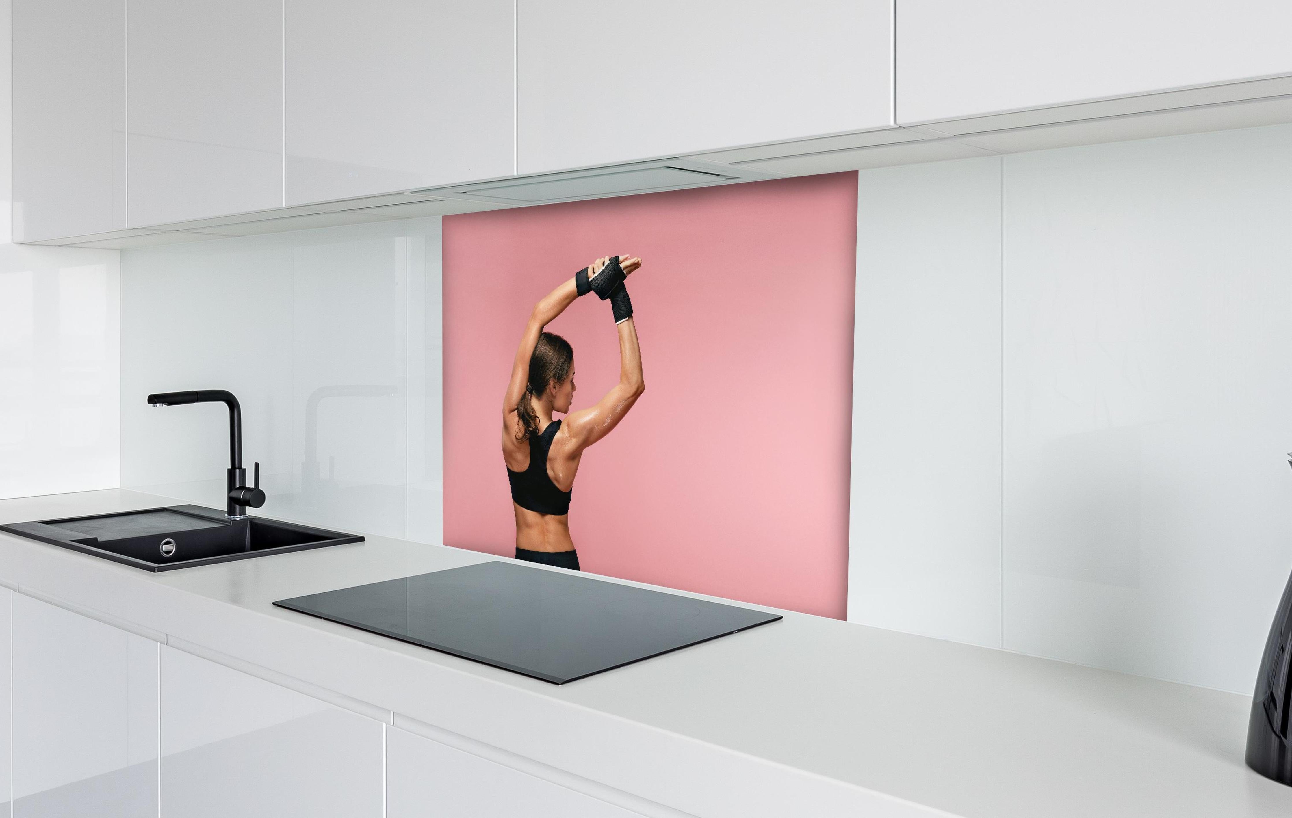 Spritzschutz - Fitness Frau streckt sich vor Training hinter einem Cerankochfeld zwischen Holz-Kochutensilien