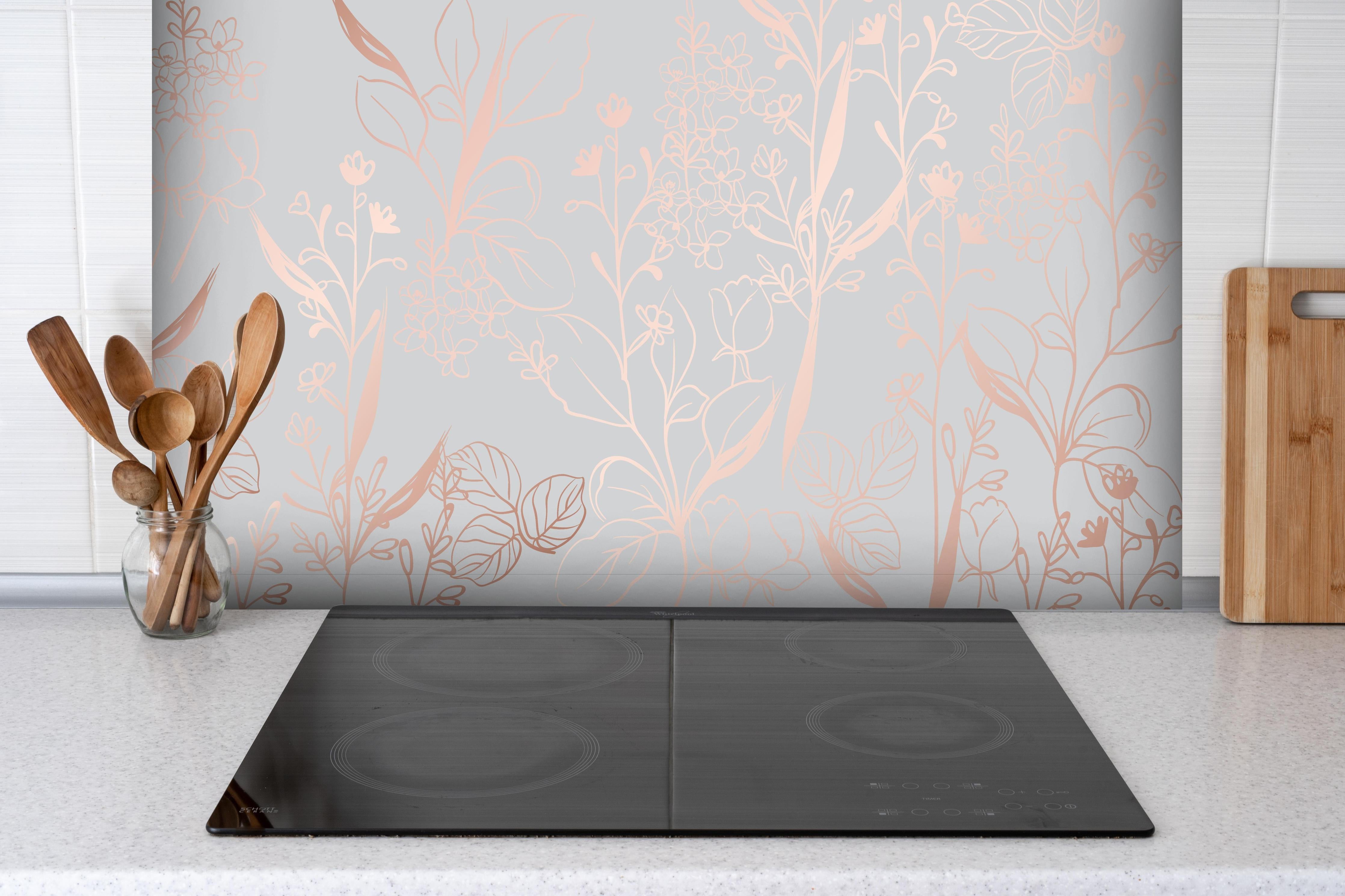 Spritzschutz - Florales Muster in Pastell Beige und Rosa hinter einem Cerankochfeld zwischen Holz-Kochutensilien