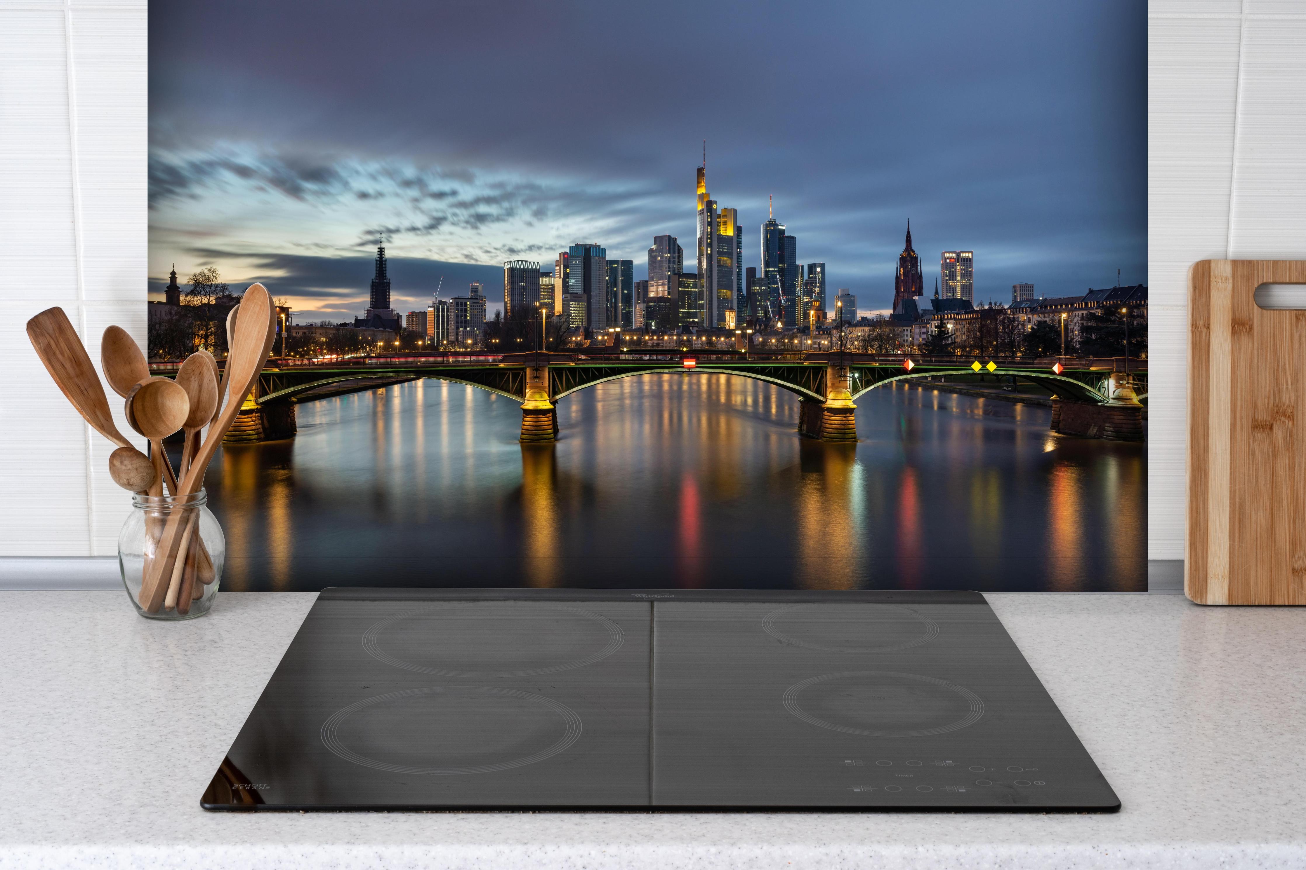 Spritzschutz - Flussansicht in der Dämmerung von Frankfurt hinter einem Cerankochfeld zwischen Holz-Kochutensilien