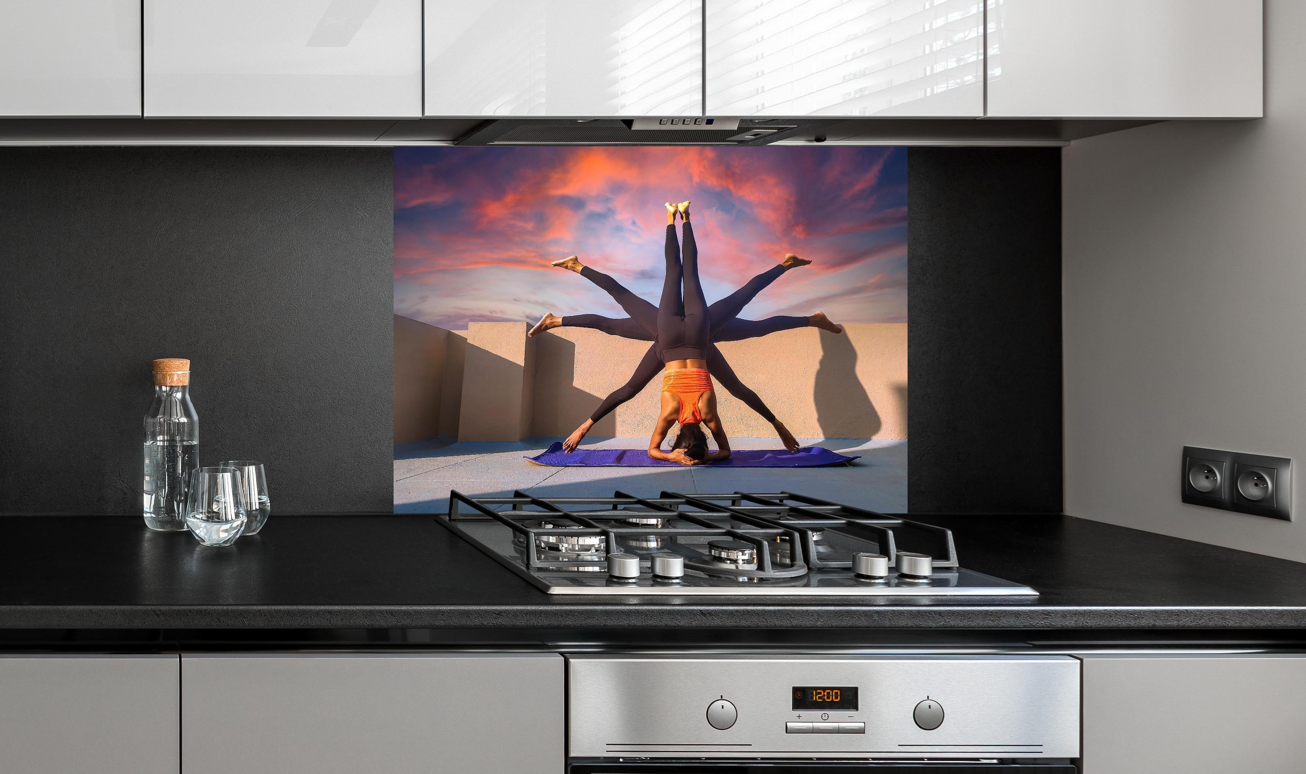 Spritzschutz - Frau Kopfstand verschiedene Posen Spirituell hinter einem Cerankochfeld zwischen Holz-Kochutensilien