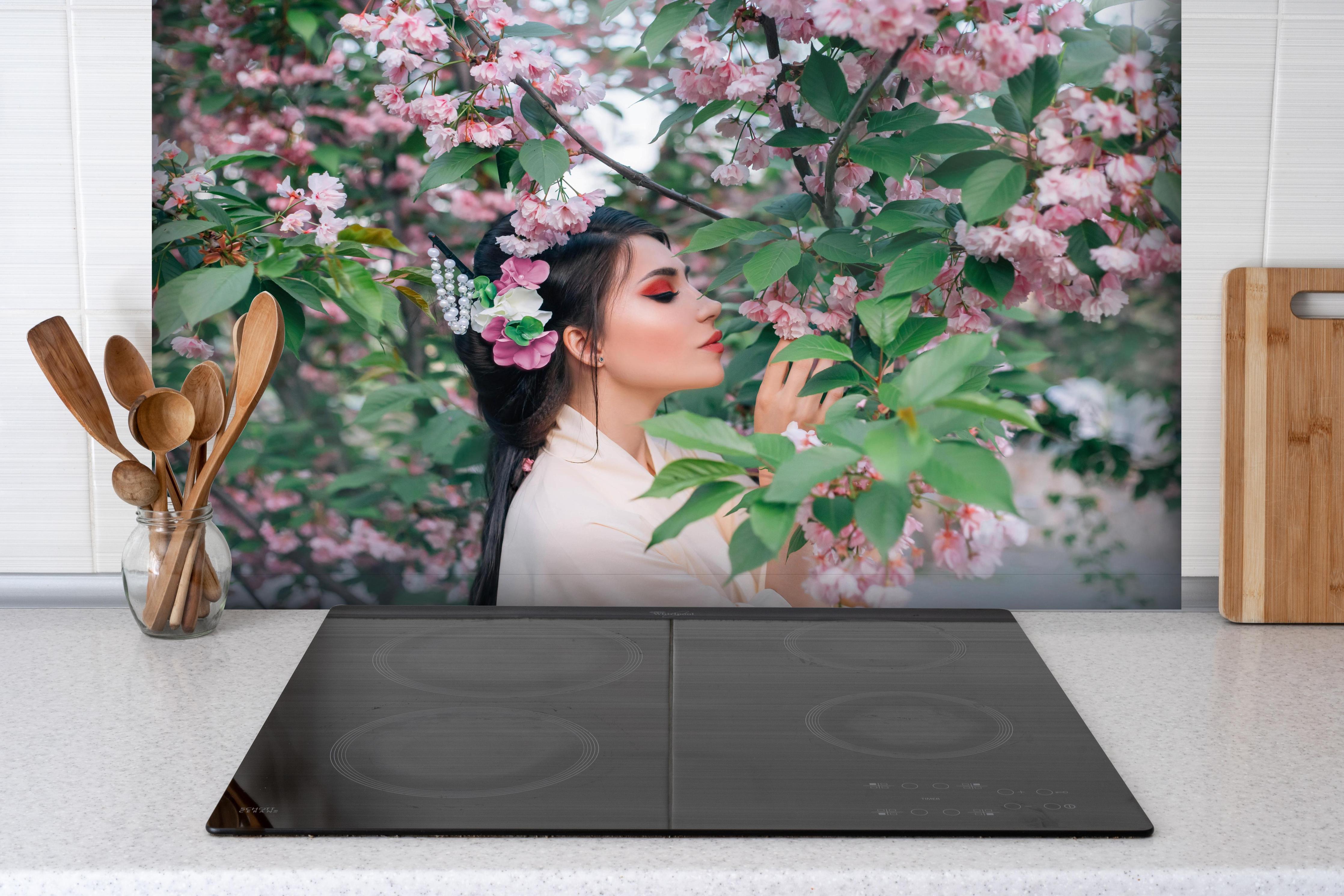 Spritzschutz - Frau in Kimono genießt Sakura-Garten hinter einem Cerankochfeld zwischen Holz-Kochutensilien