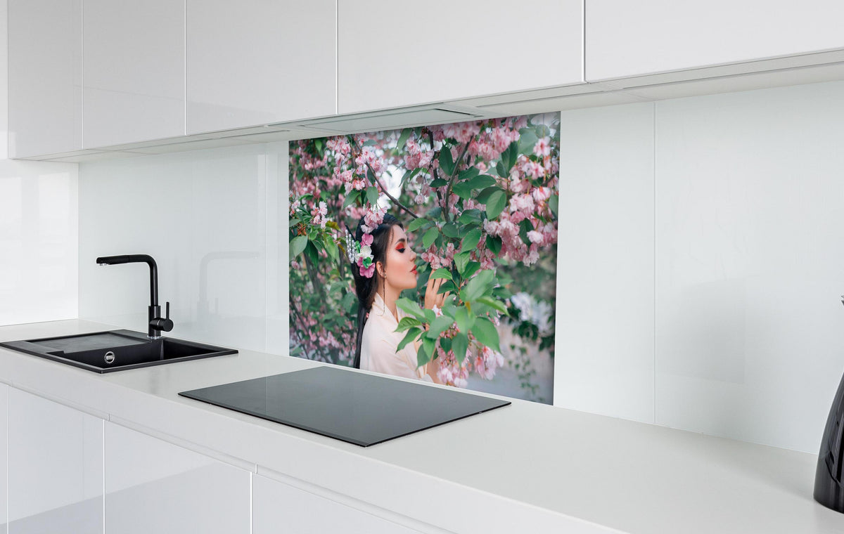 Spritzschutz - Frau in Kimono genießt Sakura-Garten hinter einem Cerankochfeld zwischen Holz-Kochutensilien
