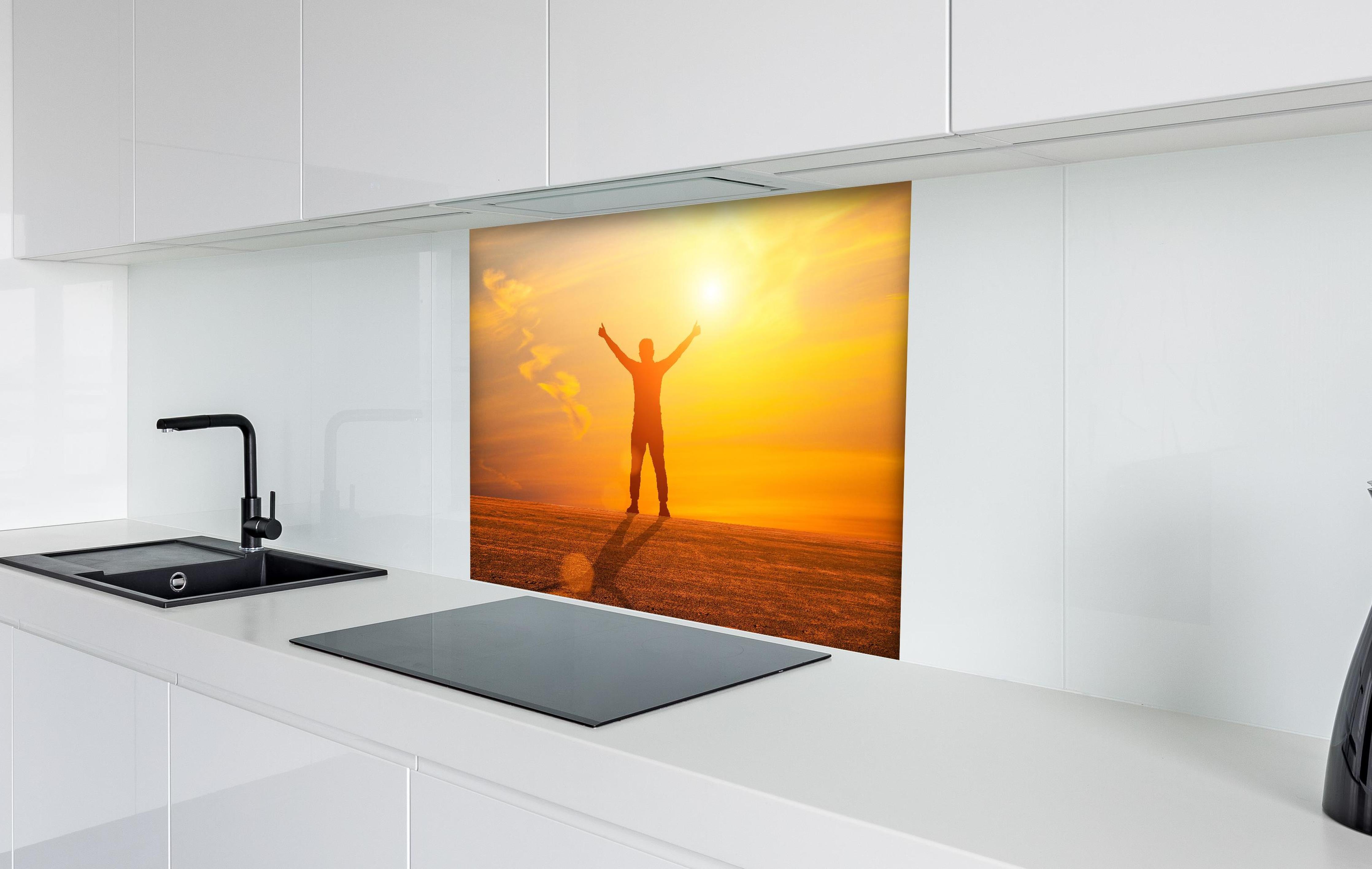 Spritzschutz - Freier Mann im goldenen Licht der Sonne hinter einem Cerankochfeld zwischen Holz-Kochutensilien