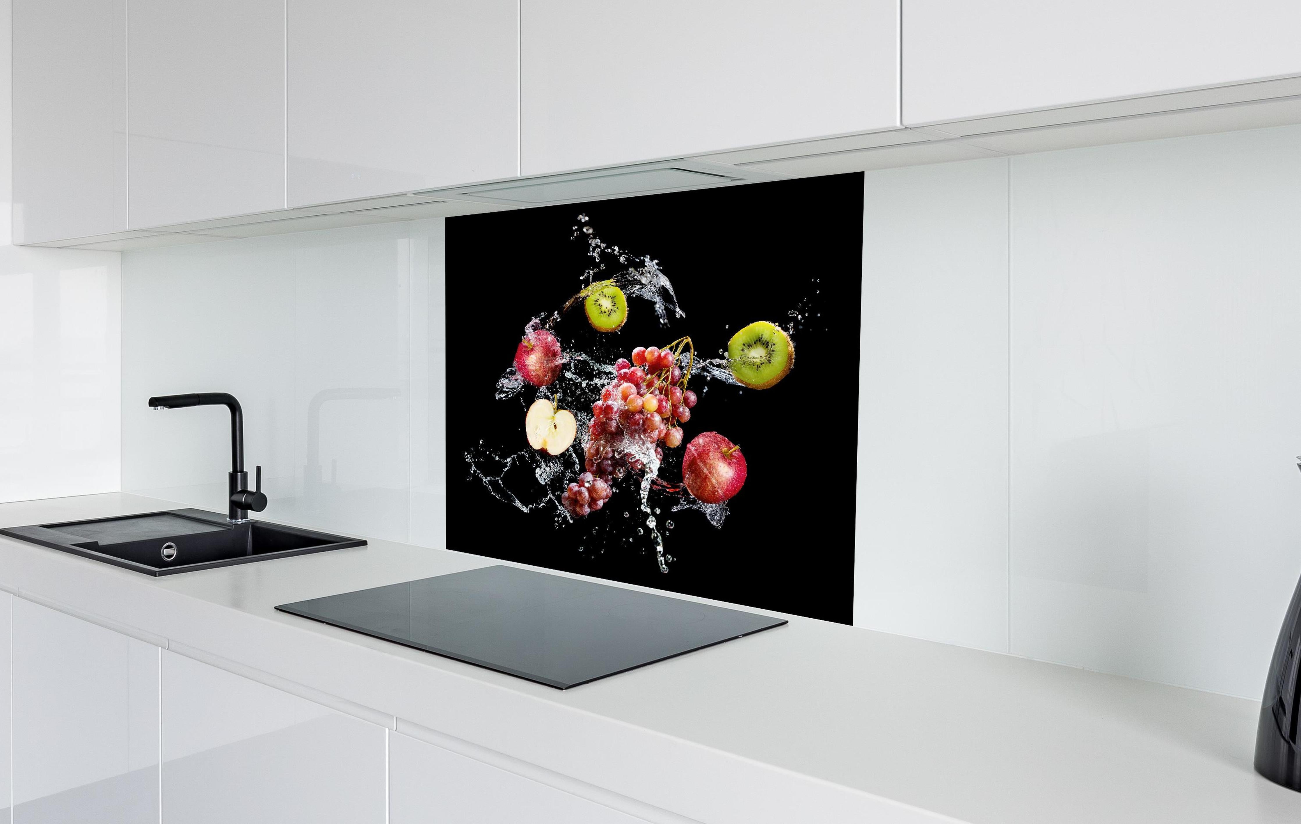 Spritzschutz - Frische Früchte im Wasser-Splash auf Schwarz hinter einem Cerankochfeld zwischen Holz-Kochutensilien