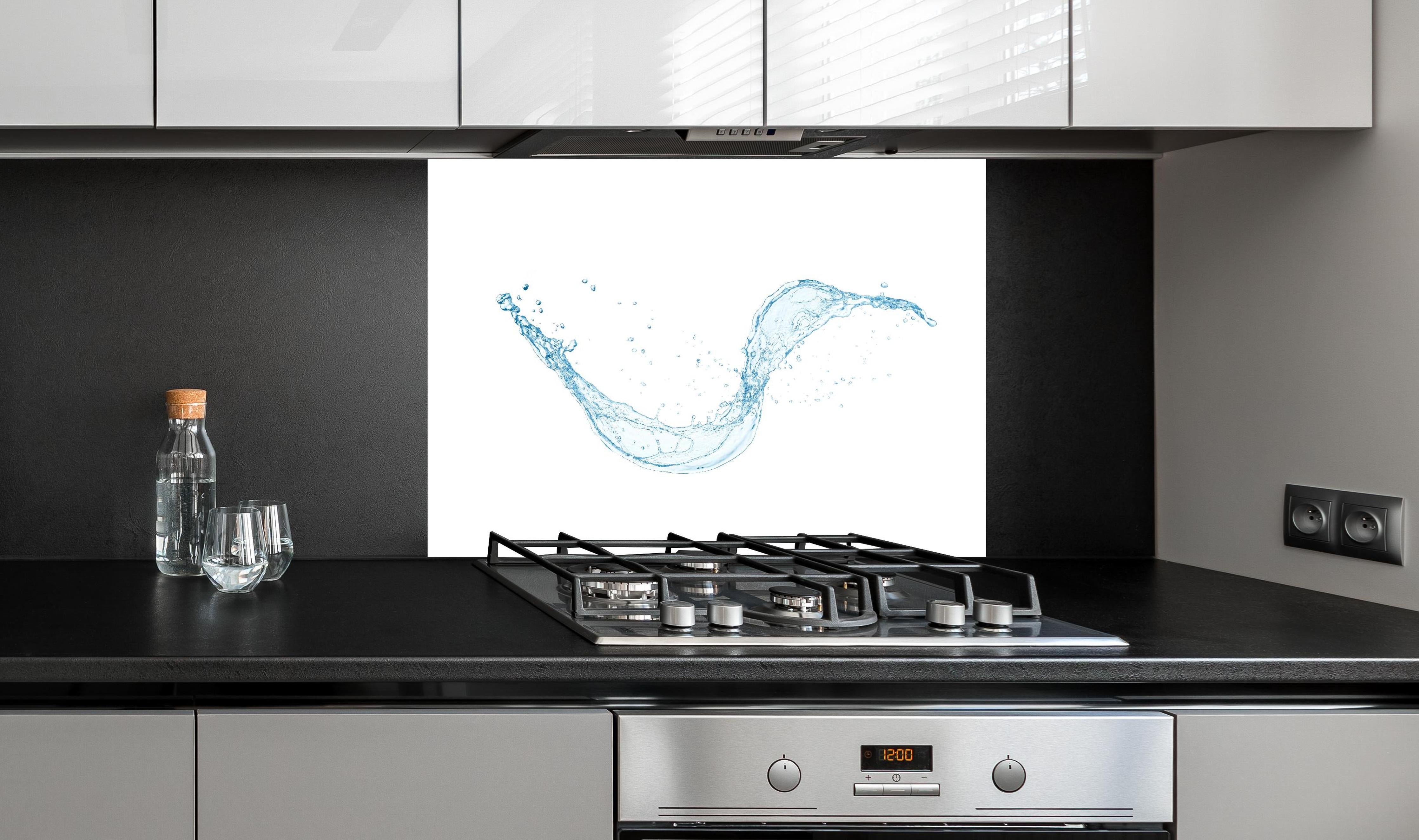 Spritzschutz - Frischer Blauer Wasser Splash Isoliert hinter einem Cerankochfeld zwischen Holz-Kochutensilien