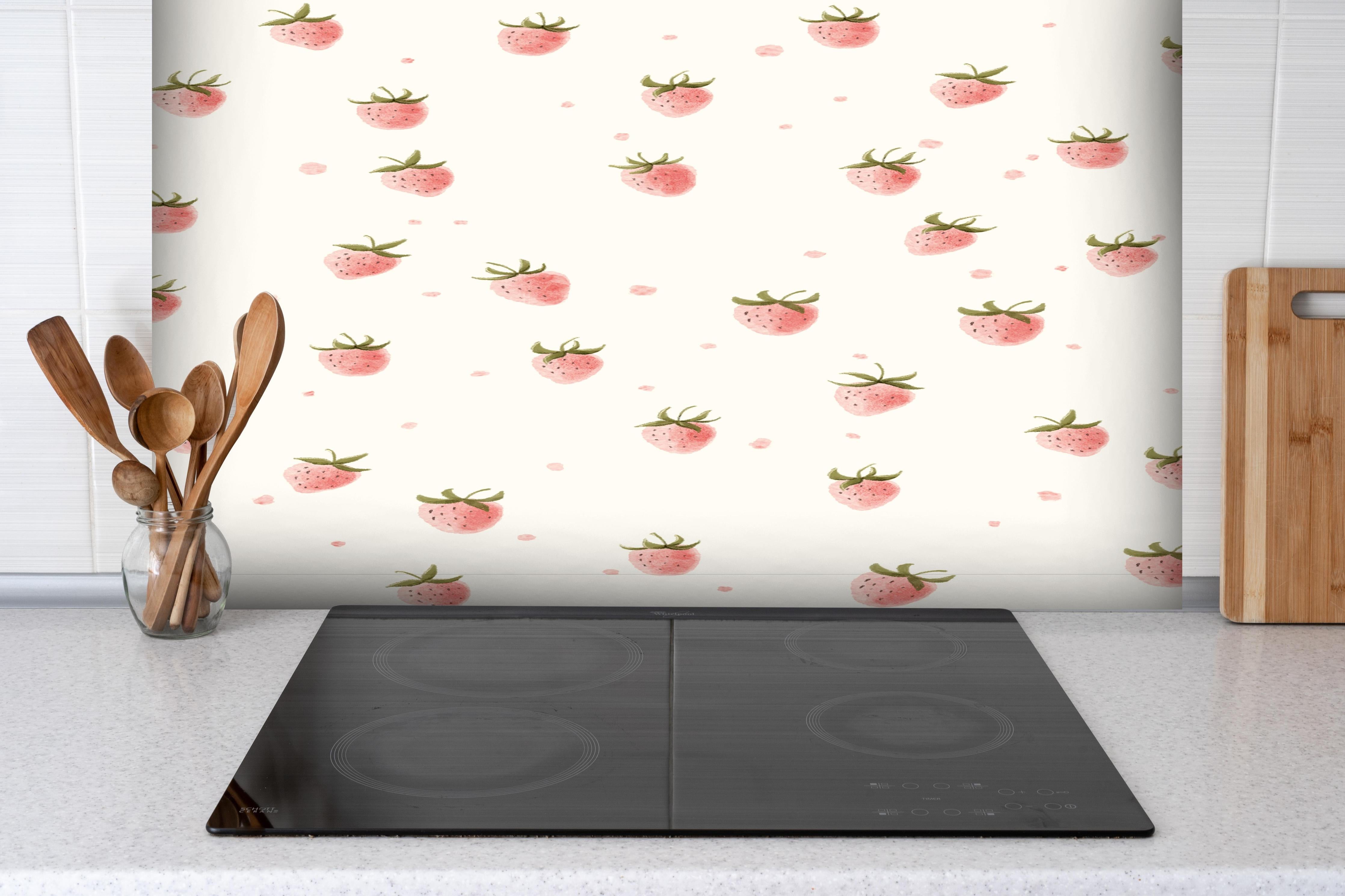 Spritzschutz - Fruchtiges Erdbeer-Muster in sanftem Rosa hinter einem Cerankochfeld zwischen Holz-Kochutensilien